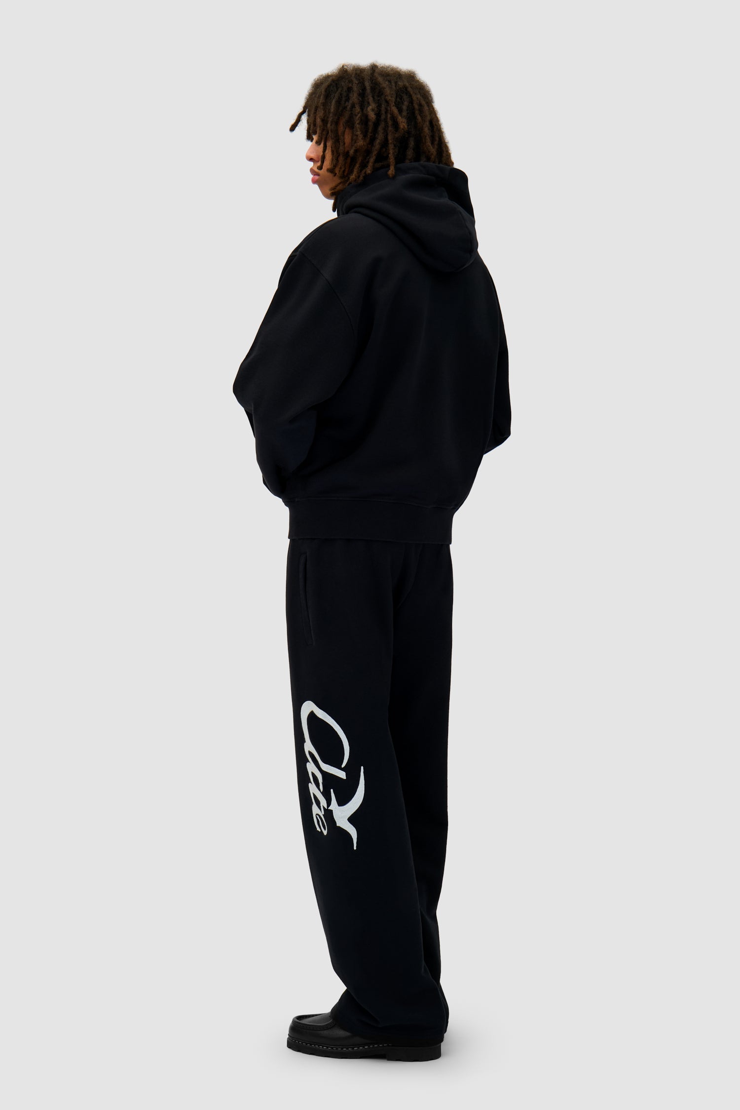 Zipper Hoodie in Black worn by a model, full-body back view