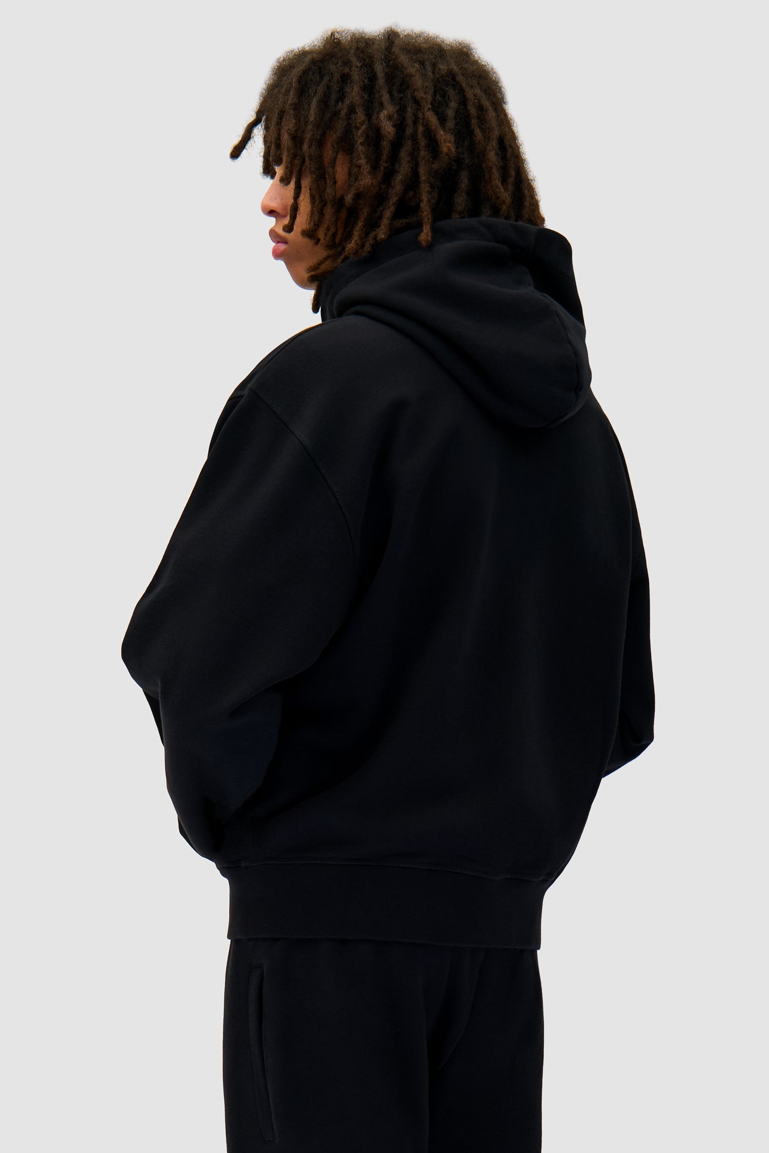 Zipper Hoodie in Black worn by a model, half-body back view