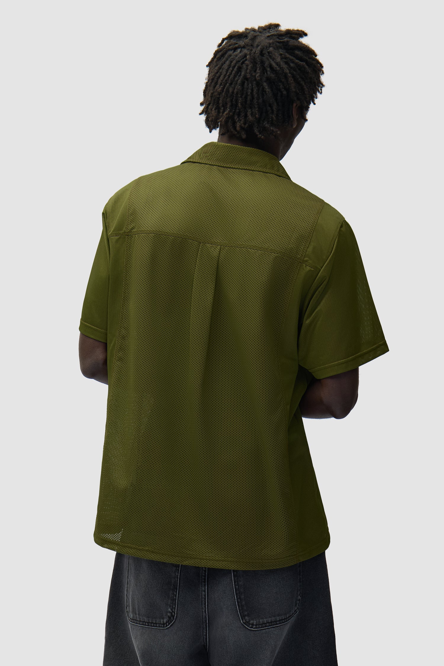 Chemise en maille verte portée par un mannequin, vue de dos à mi-corps