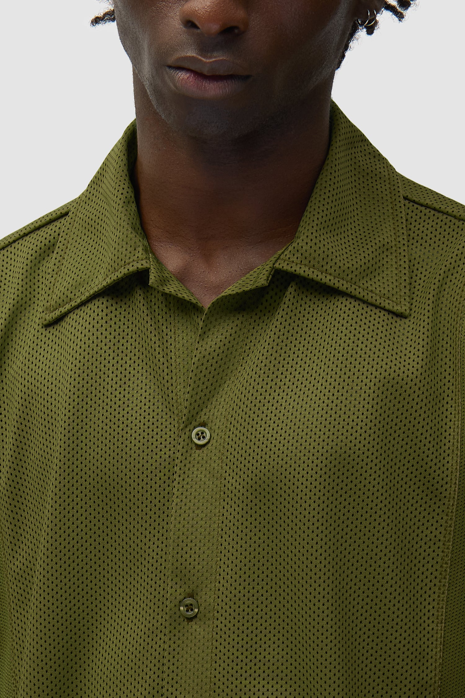 Chemise en maille verte portée par un mannequin, vue de profil à mi-corps