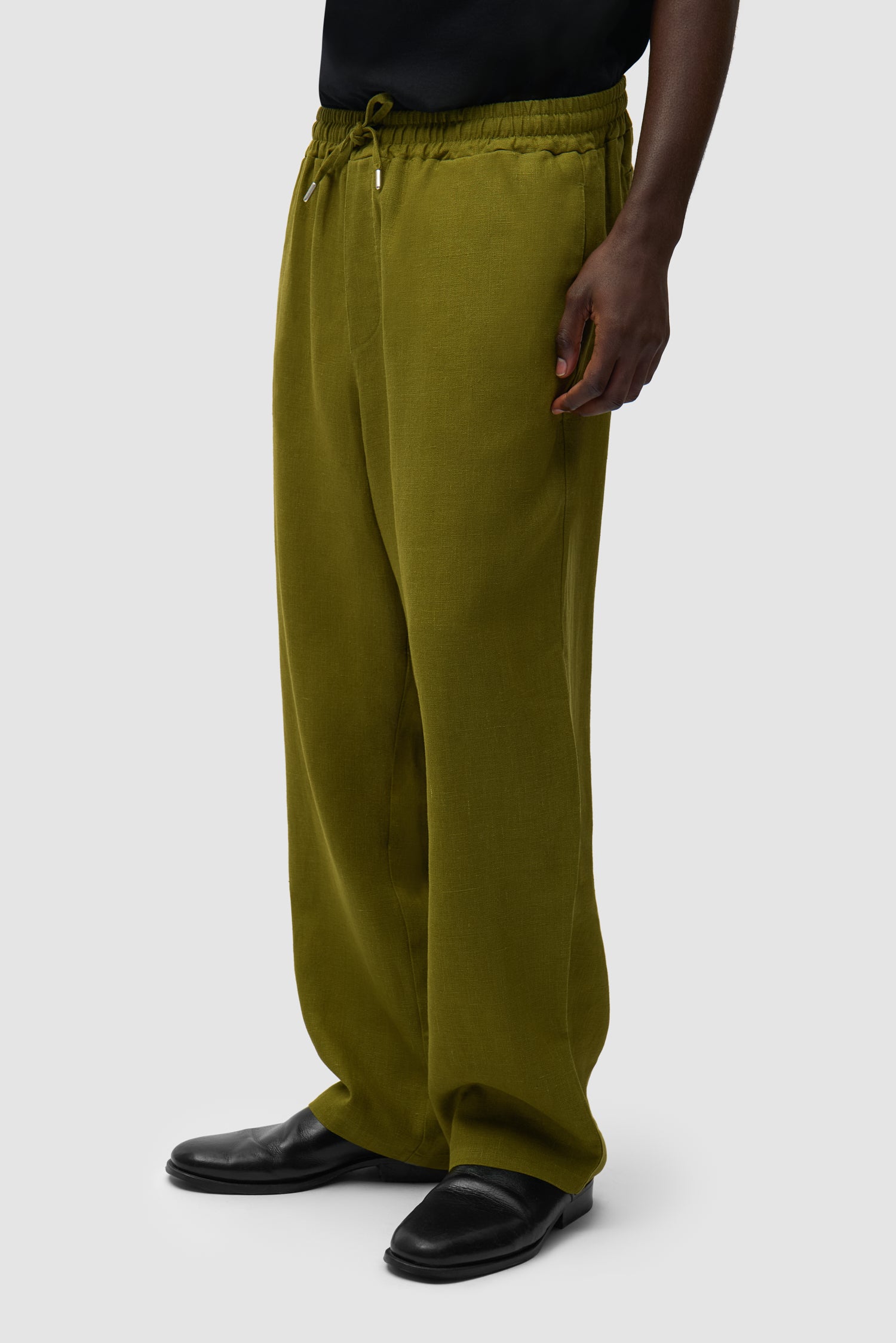 Pantalon en lin vert porté par un mannequin, vue de profil à mi-corps