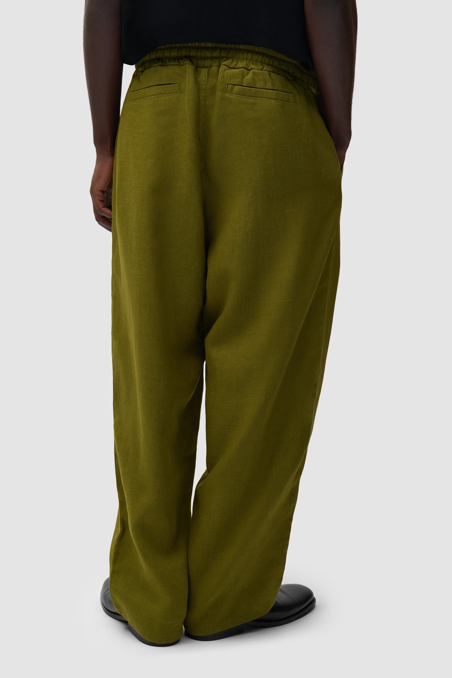 Pantalon en lin vert porté par un mannequin, vue de dos à mi-corps