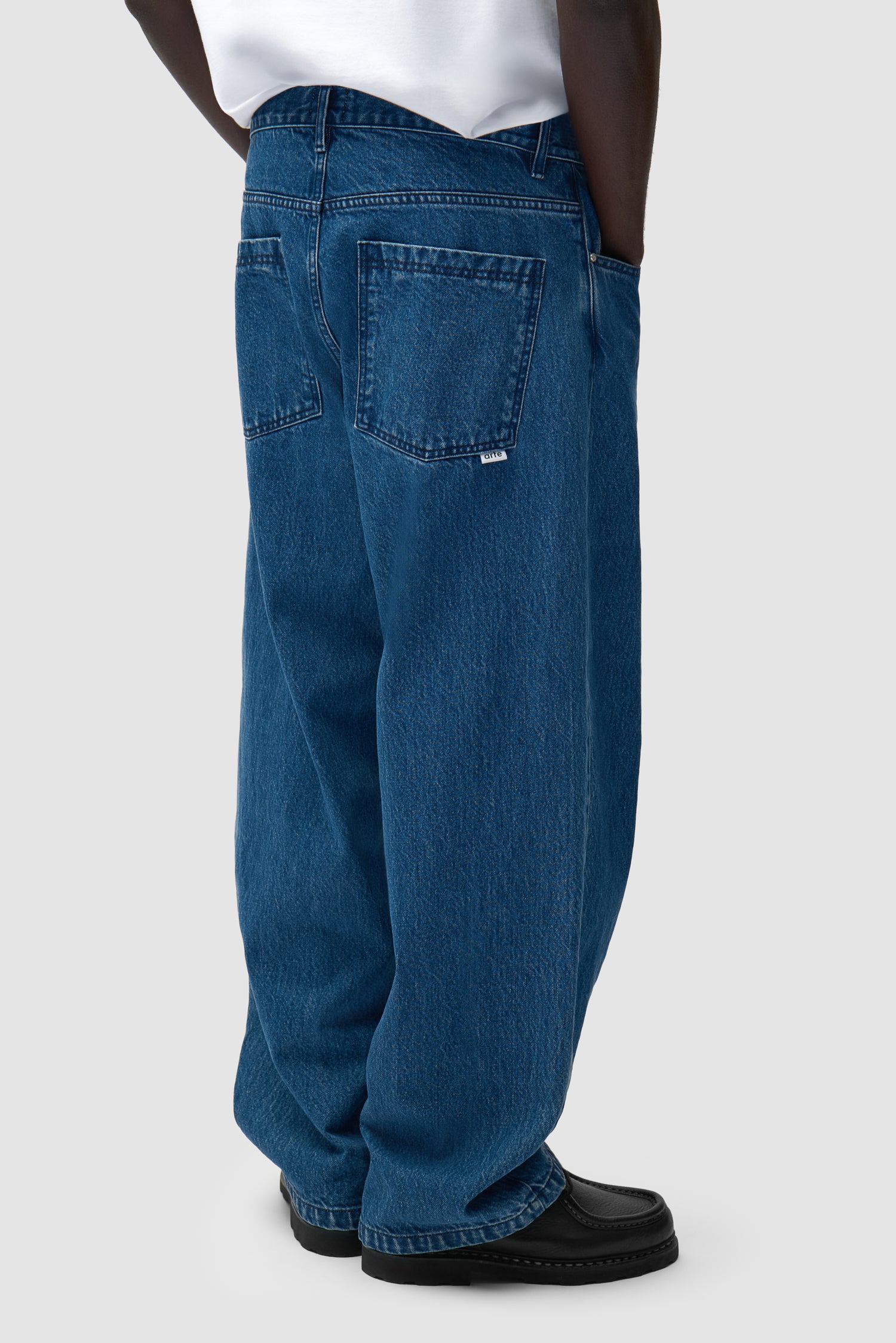 Pantalon baggy en denim brut porté par un mannequin, vue de dos à mi-corps