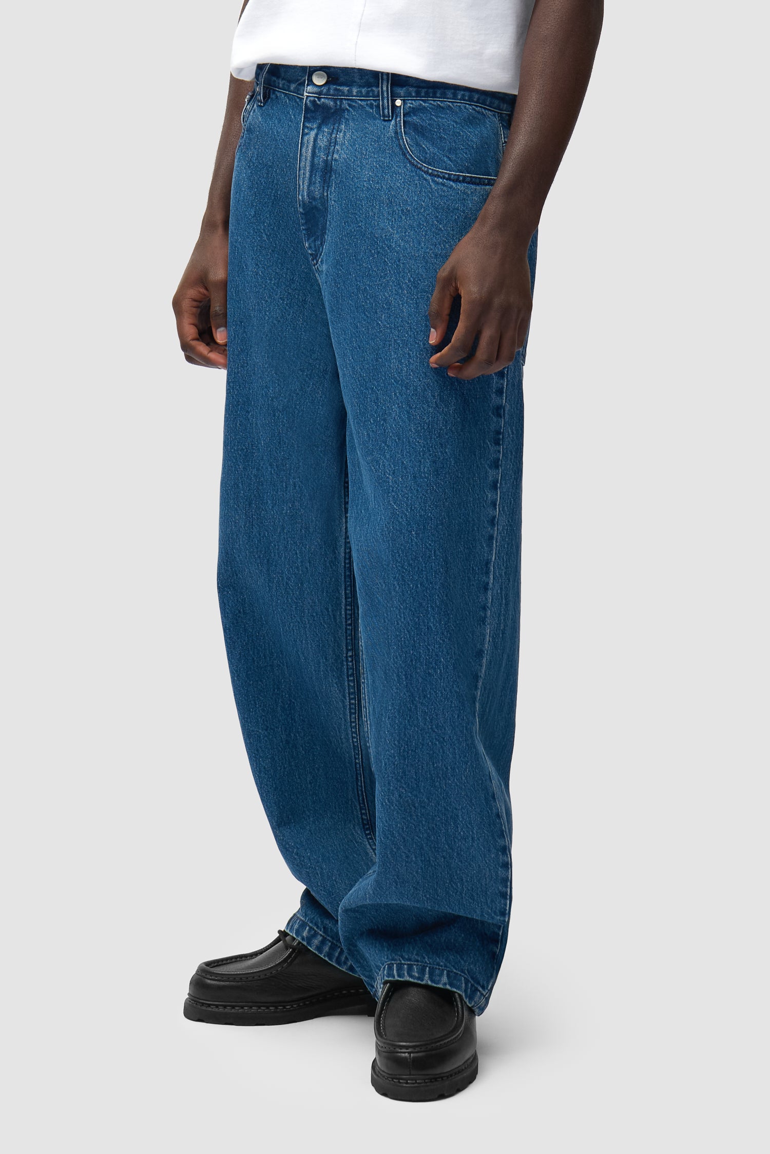 Pantalon baggy en denim brut porté par un mannequin, vue de profil à mi-corps