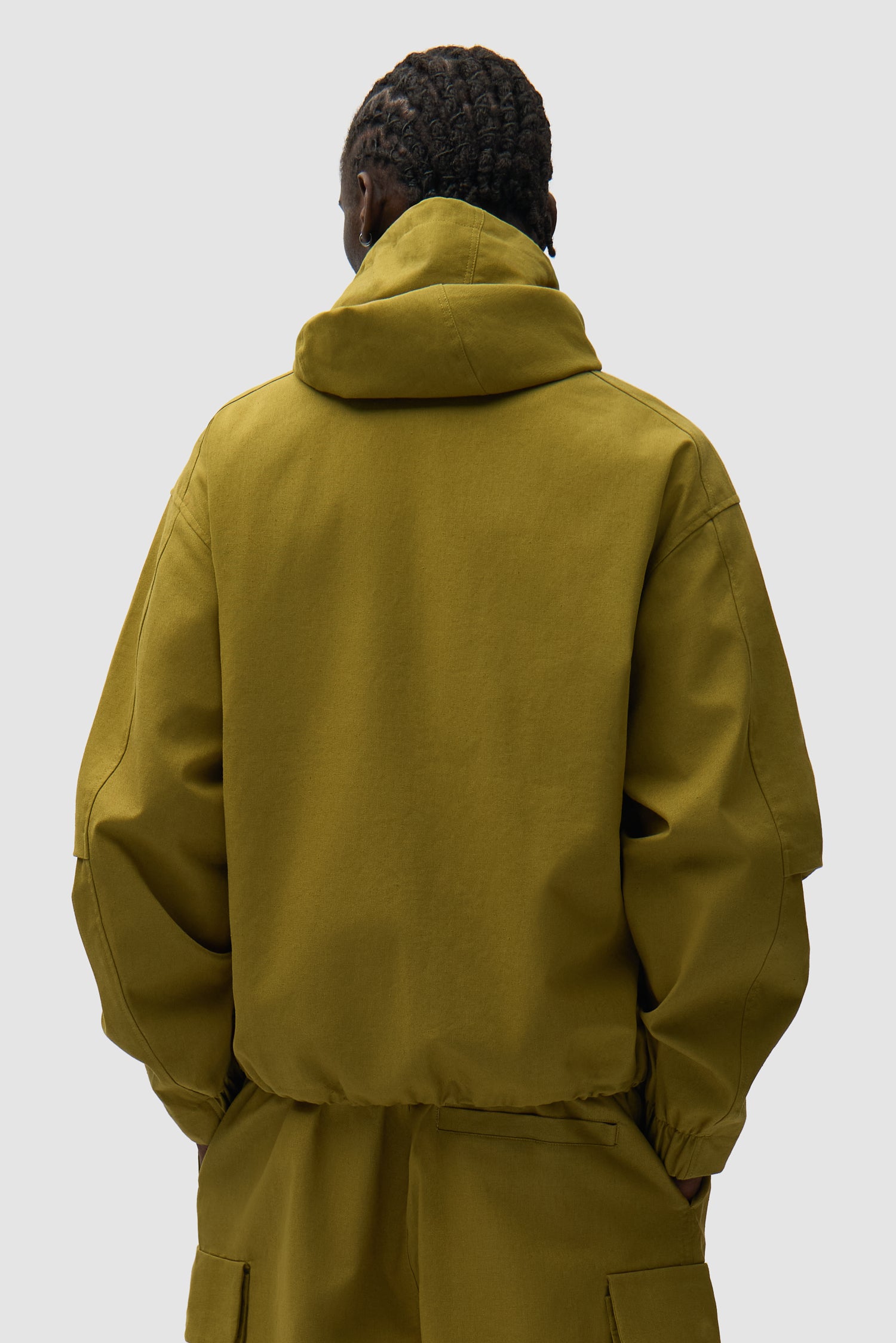 Veste technique en lin verte portée par un mannequin, vue de dos à mi-corps