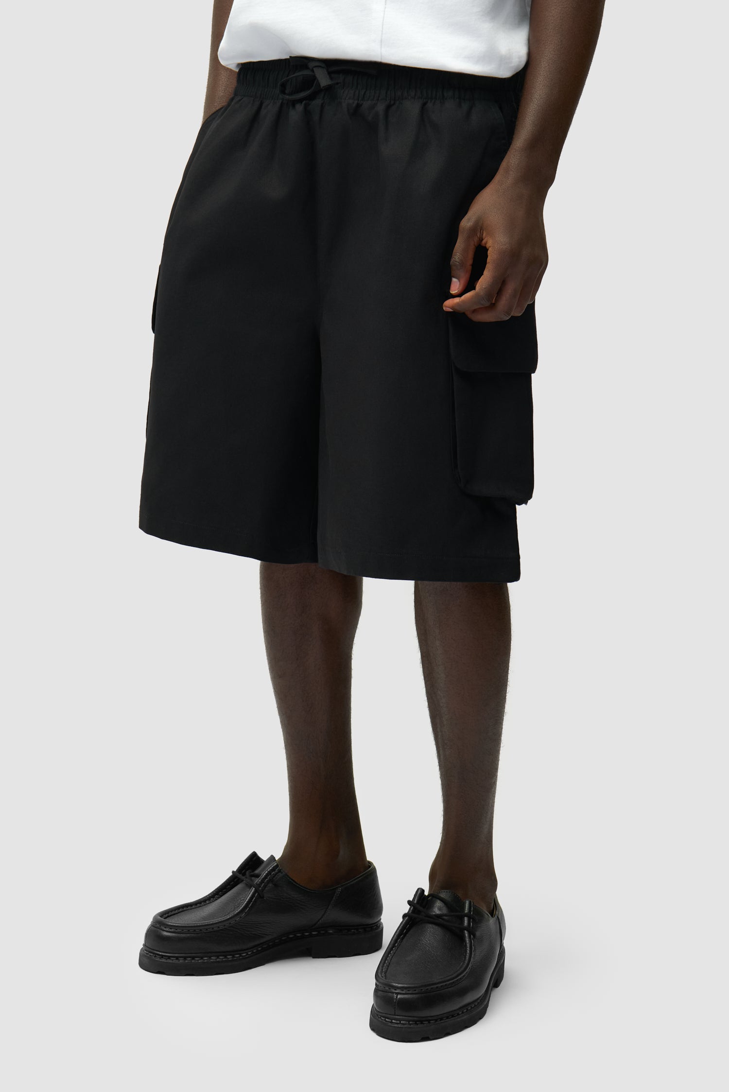 Short cargo en lin noir porté par un mannequin, vue de face en demi-corps