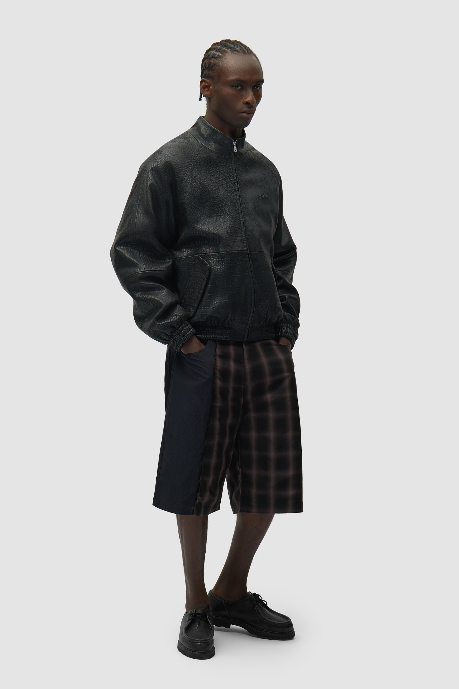 Veste en cuir à col haut, couleur noire, portée par un mannequin, vue de profil en pied