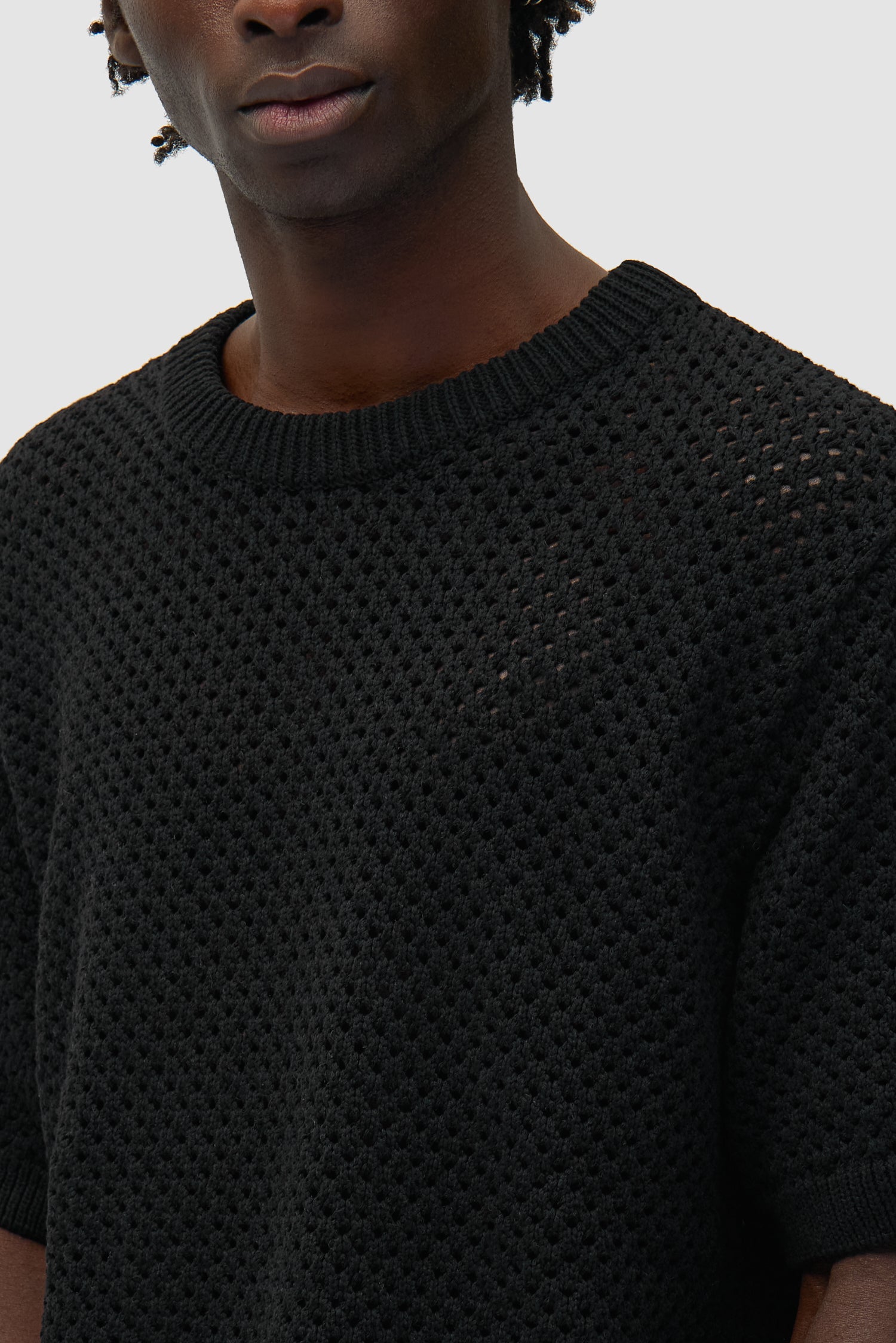 Vue détaillée du t-shirt au crochet noir, montrant le motif tricoté