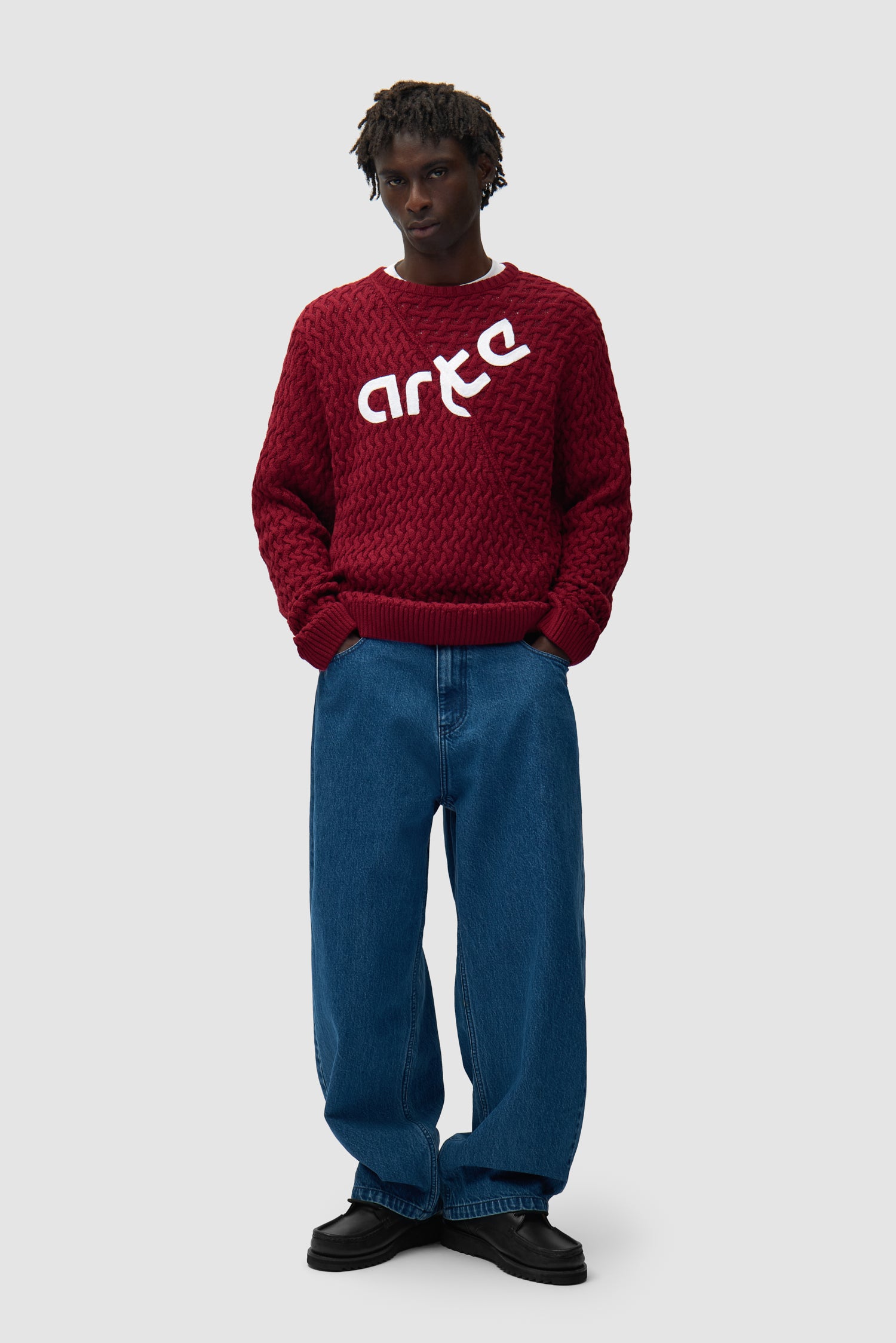 Pull à logo déformé couleur bordeaux porté par un mannequin, vue de face en pied