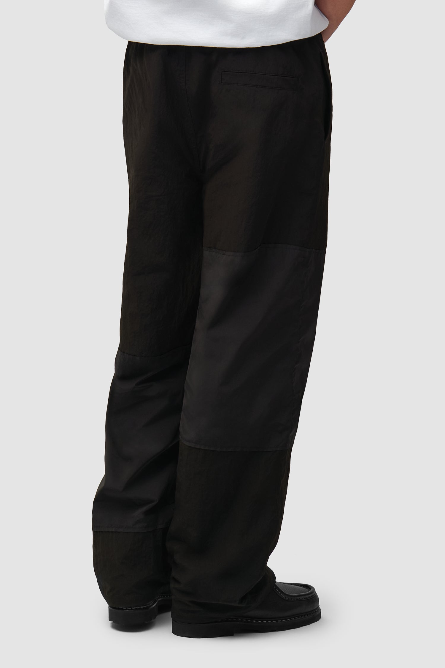 Pantalon de survêtement carré noir porté par un mannequin, vue de dos à mi-corps