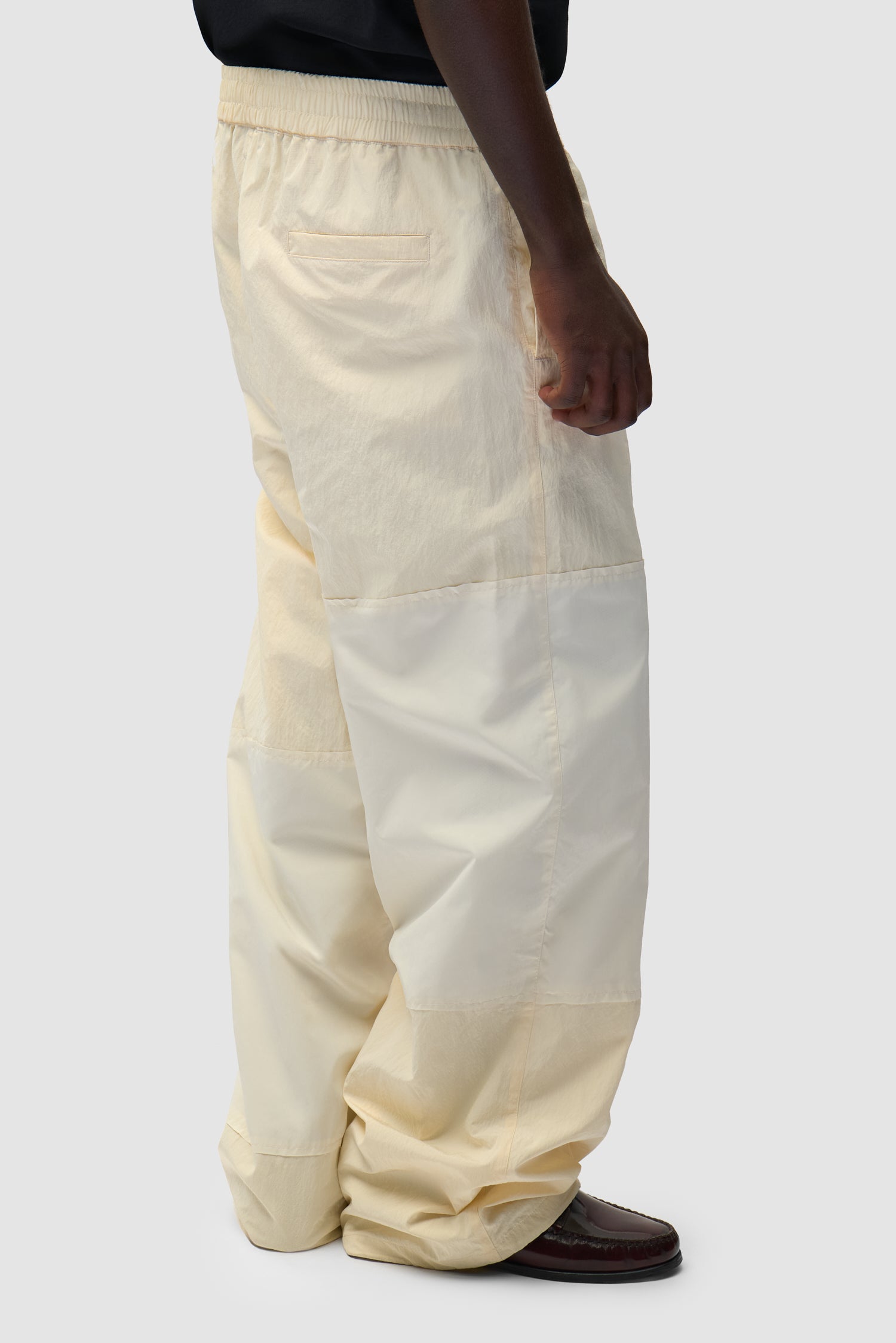 Pantalon de survêtement carré couleur crème porté par un mannequin, vue de dos à mi-corps