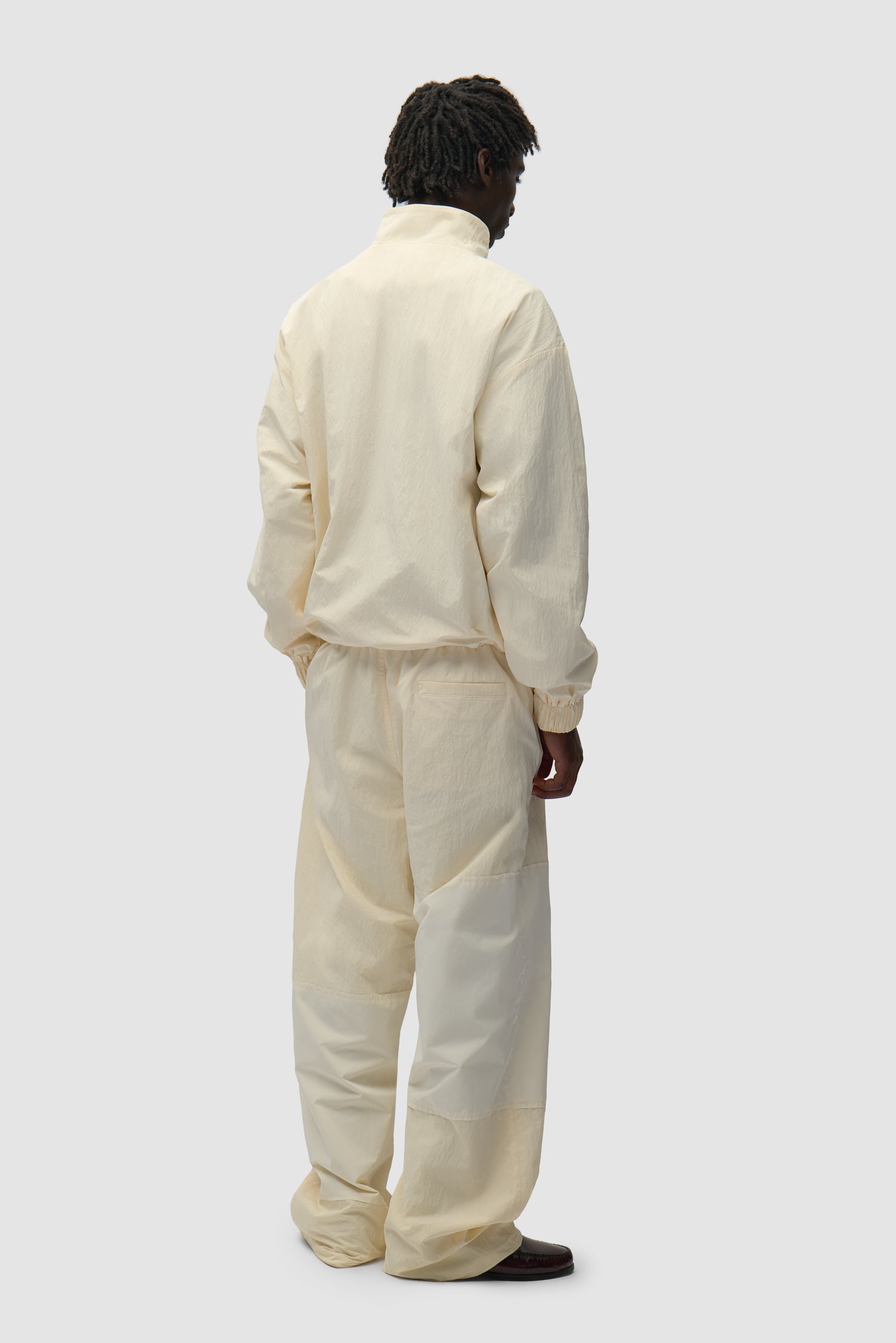 Pantalon de survêtement à carreaux couleur crème porté par un mannequin, vue de profil en pied