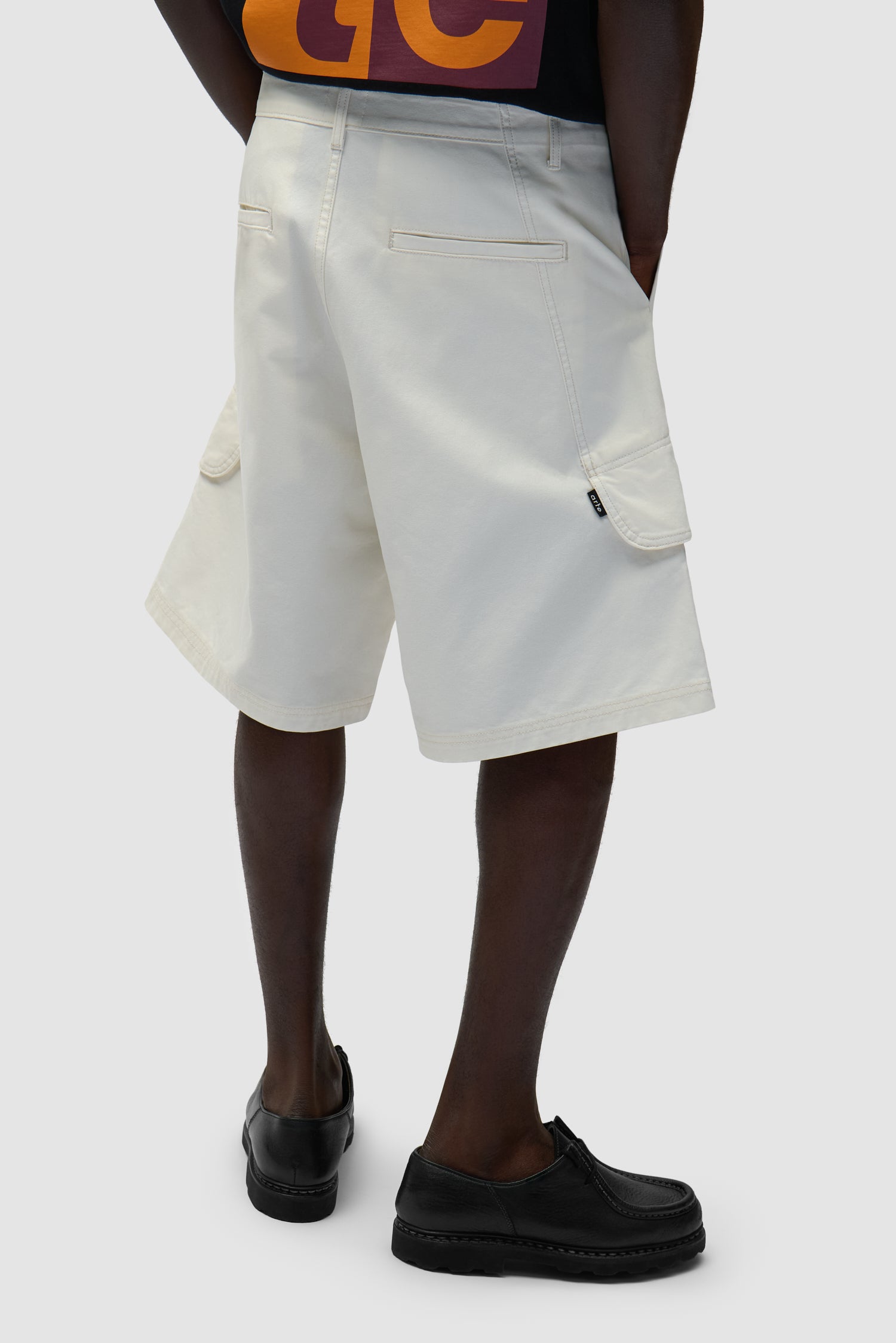 Short cargo en toile couleur crème porté par un mannequin, vue de dos à mi-corps