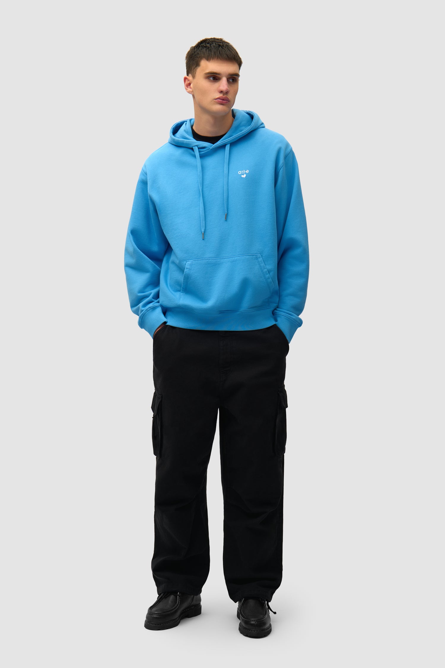 Heart Logo Hoodie in Blue worn by a model, full-body side view