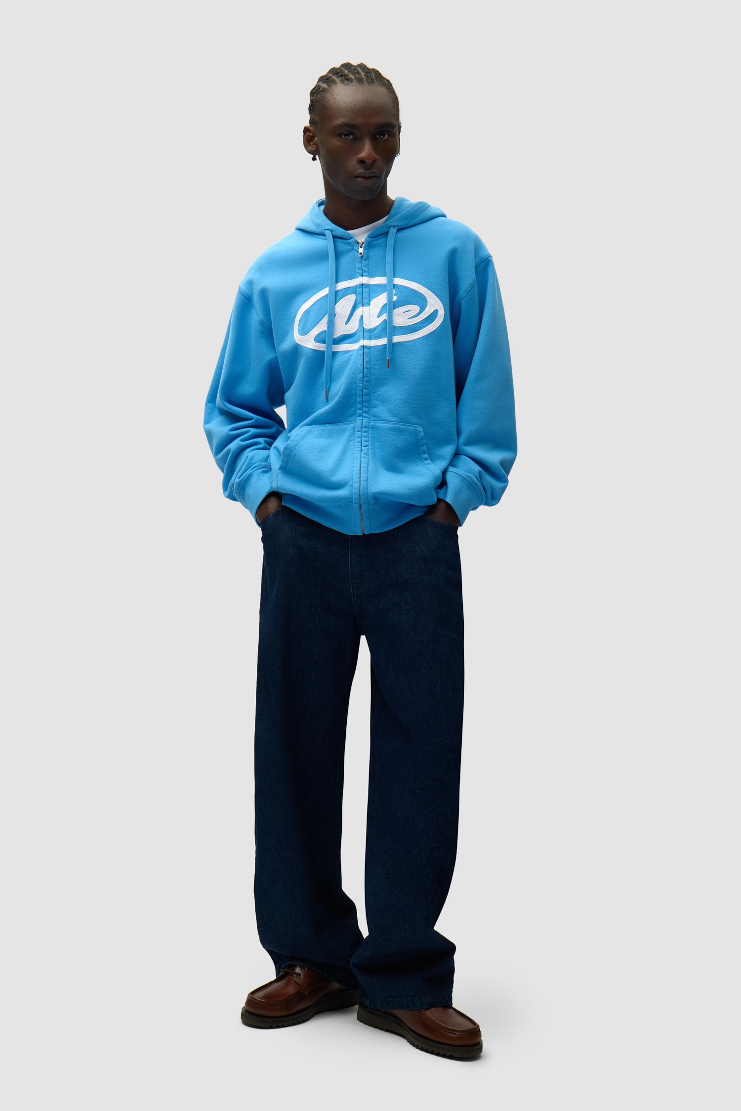 Sweat à capuche zippé avec logo circulaire bleu porté par un mannequin, vue de face en pied