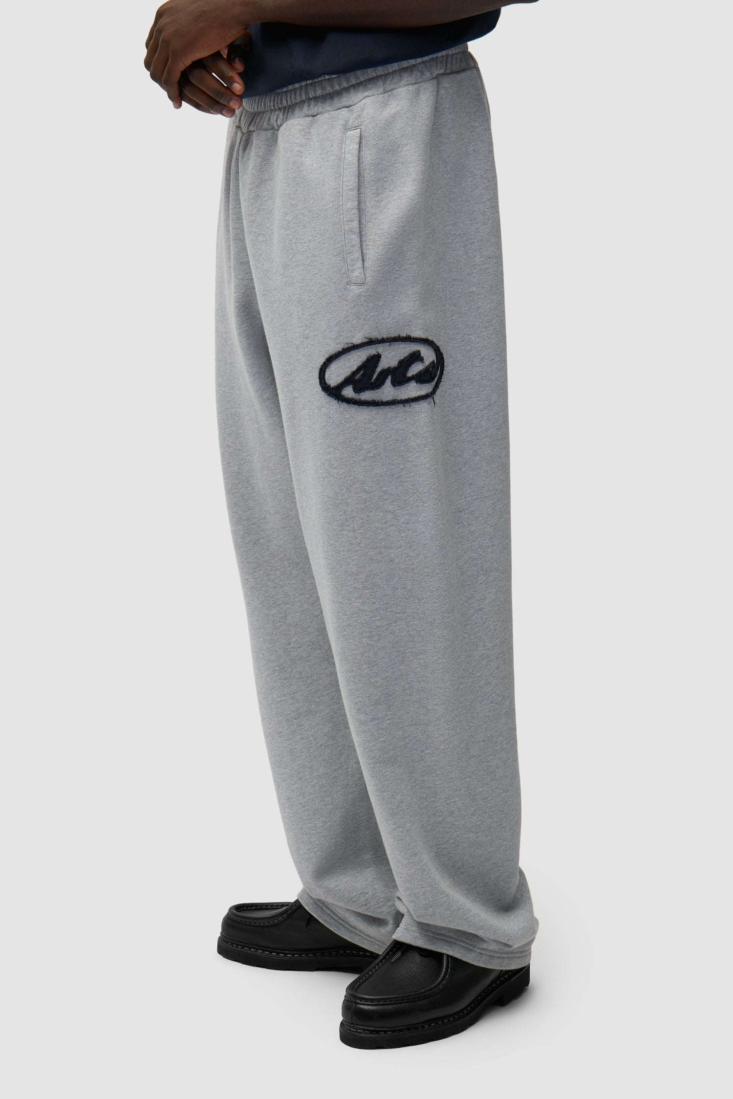 Pantalon de survêtement gris avec logo Circle Patch porté par un mannequin, vue de profil à mi-corps