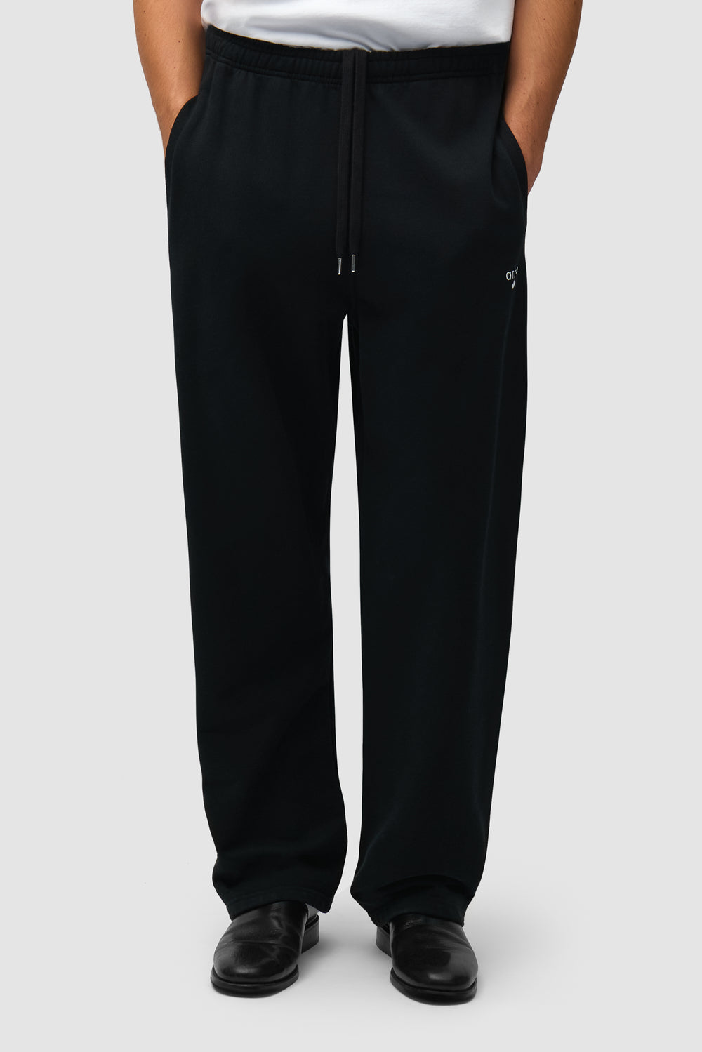 Pantalon de survêtement noir avec logo en forme de cœur porté par un mannequin, vue de face en demi-corps