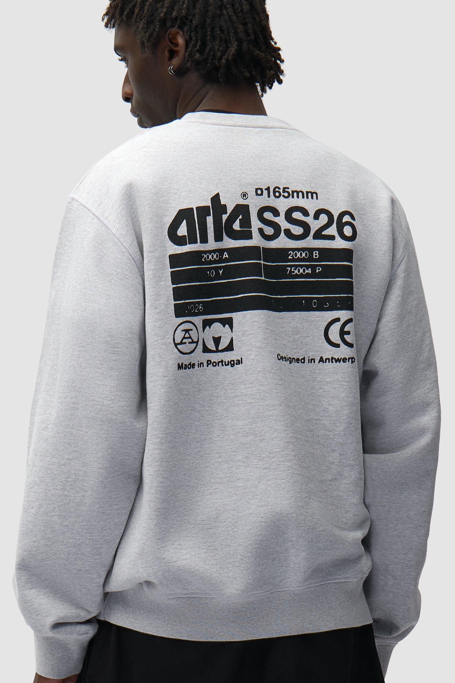 Dos SS26 Crewneck en gris porté par un mannequin, vue de profil à mi-corps