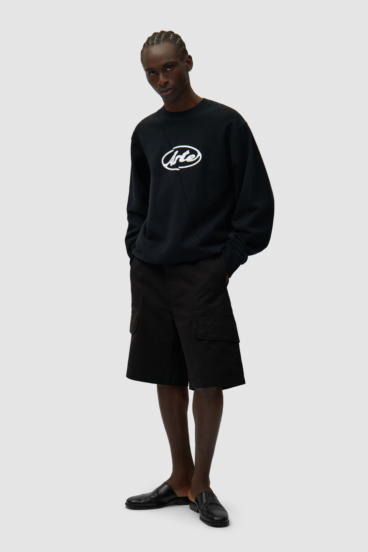 Pull noir avec logo brodé en cercle porté par un mannequin, vue de profil en pied