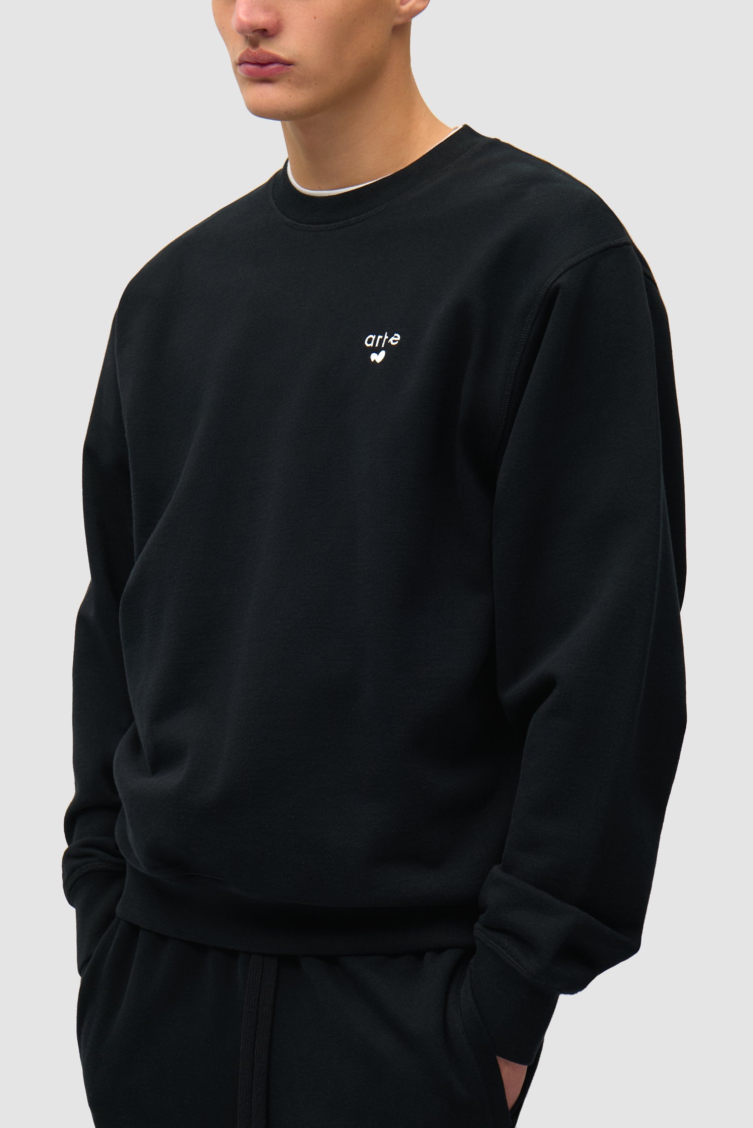 T-shirt à col rond noir avec logo en forme de cœur porté par un mannequin, vue de profil