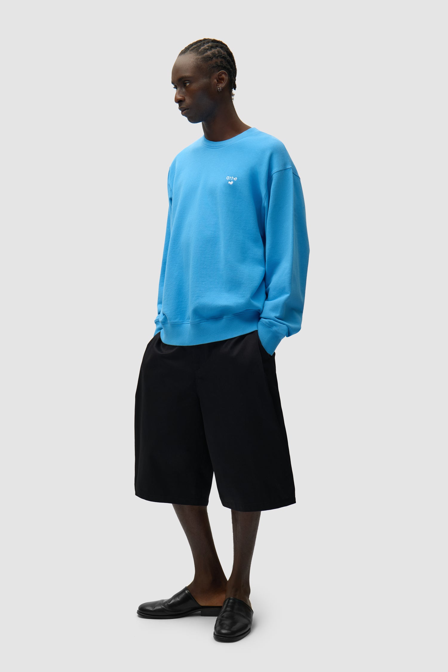 T-shirt à col rond avec logo en forme de cœur, couleur bleue, porté par un mannequin, vue de profil en pied