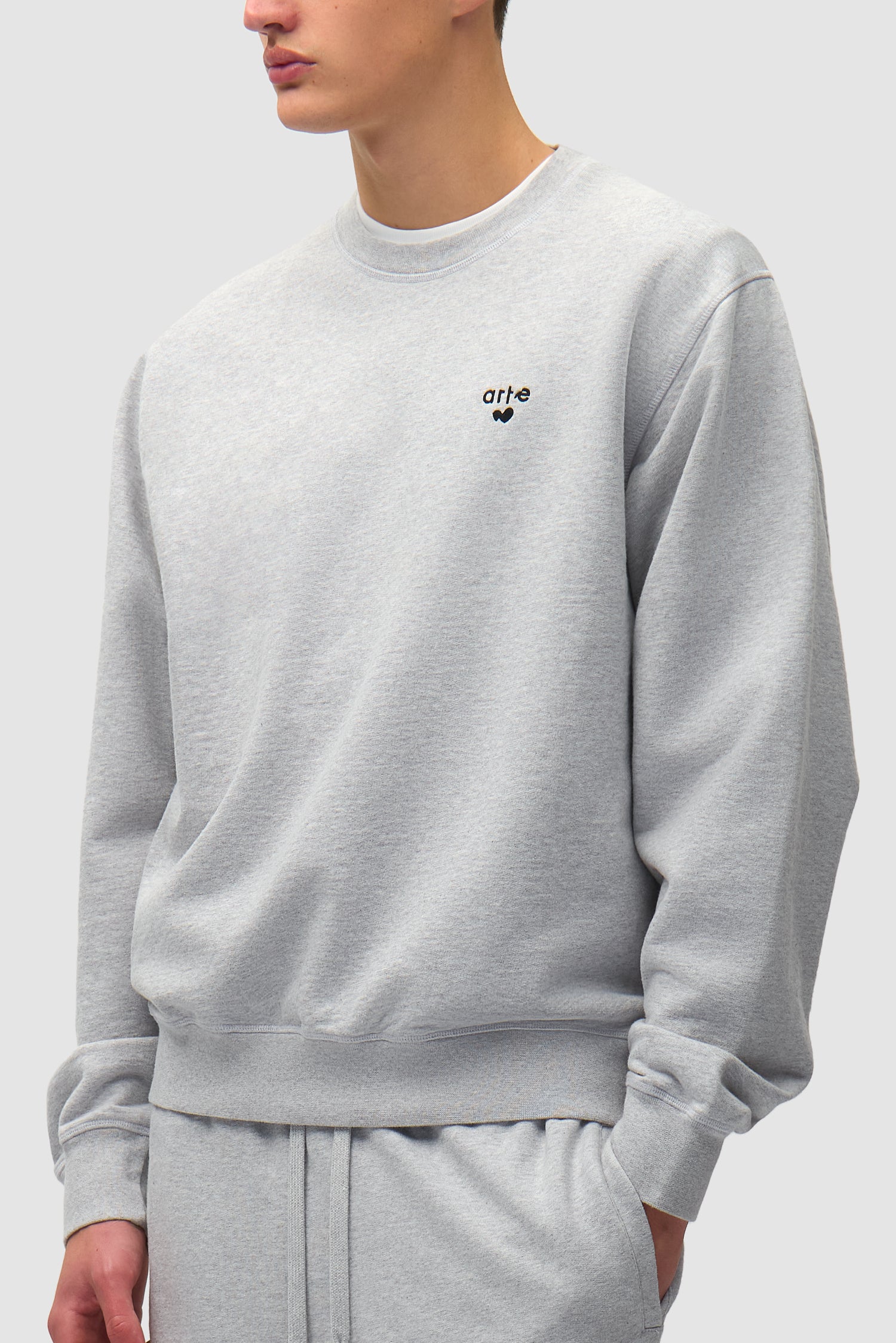 T-shirt à col rond avec logo en forme de cœur, couleur grise, porté par un mannequin, vue de profil