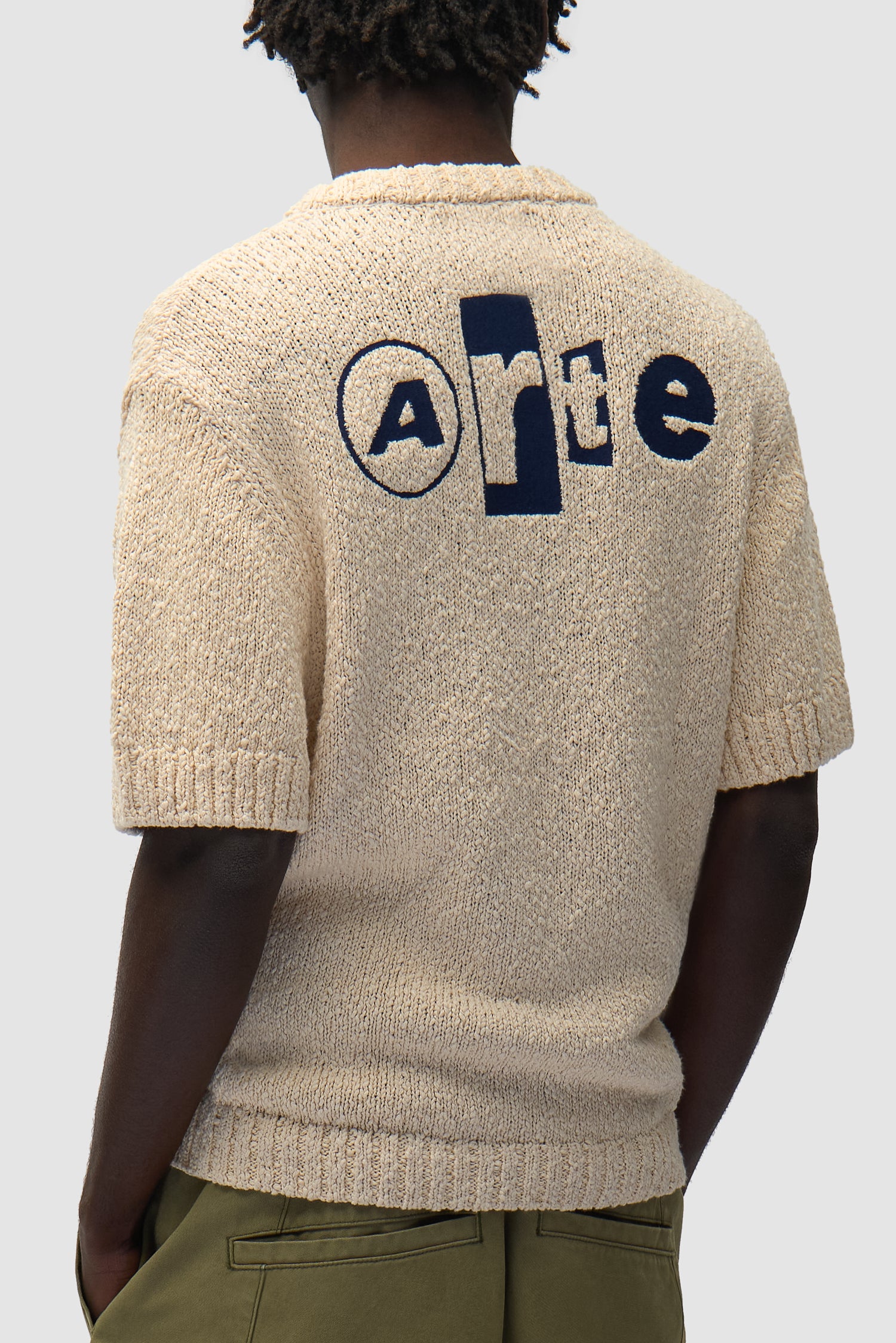 T-shirt en maille avec motif graphique dans le dos, couleur crème, porté par un mannequin, vue de profil