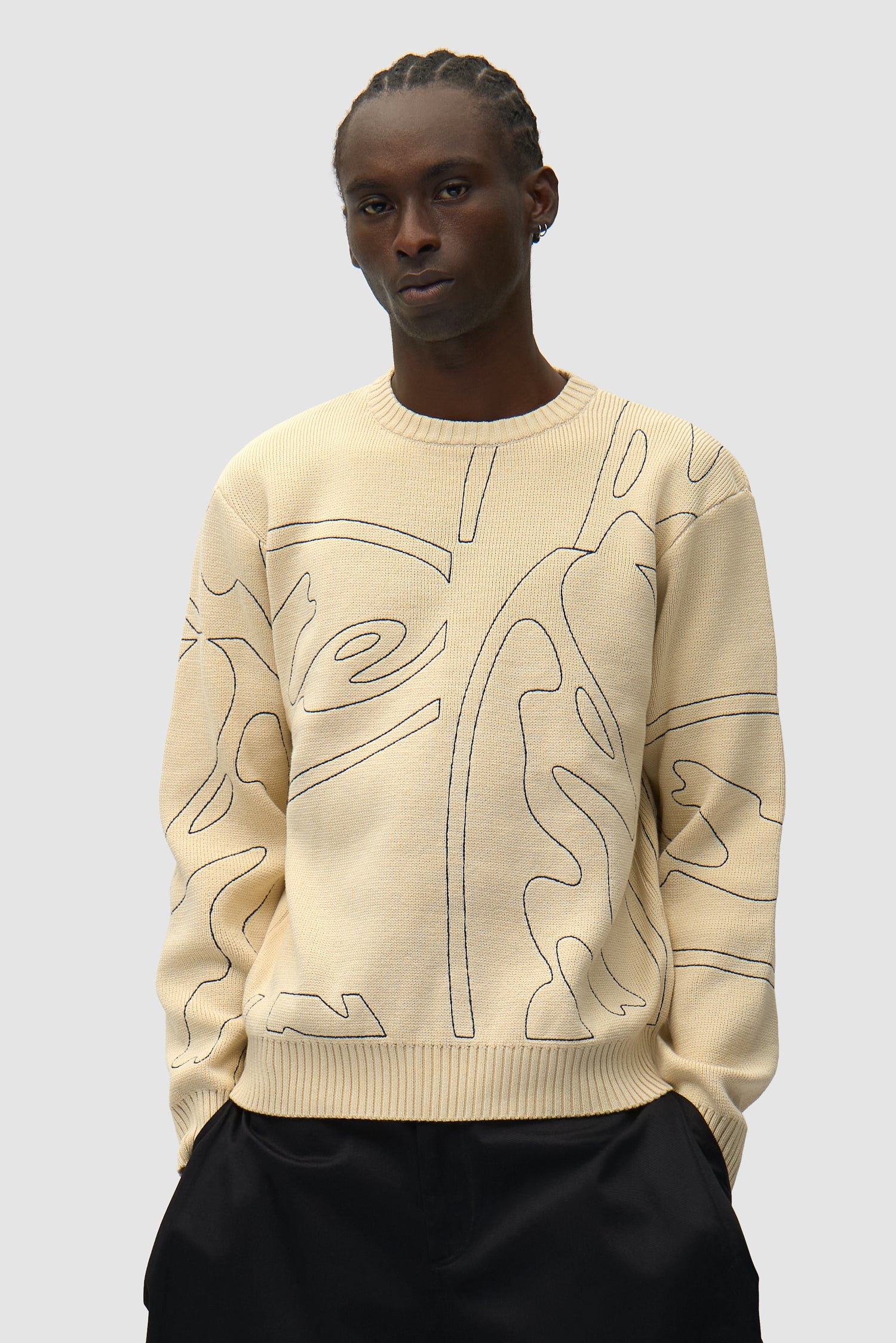 Tricot à logo circulaire intégral couleur crème porté par un mannequin, vue de face en demi-corps