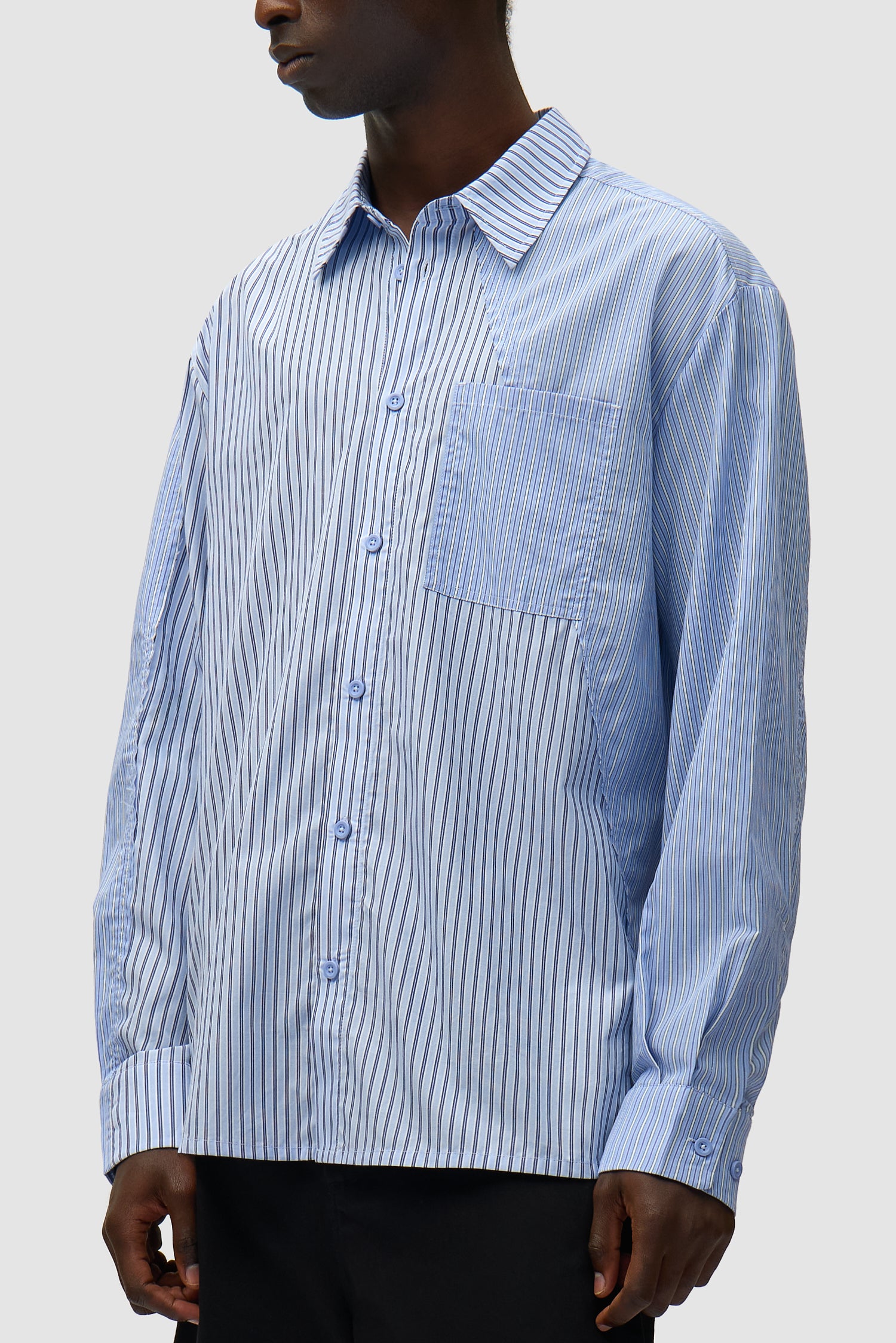 Chemise longue asymétrique à rayures portée par un mannequin, vue de profil