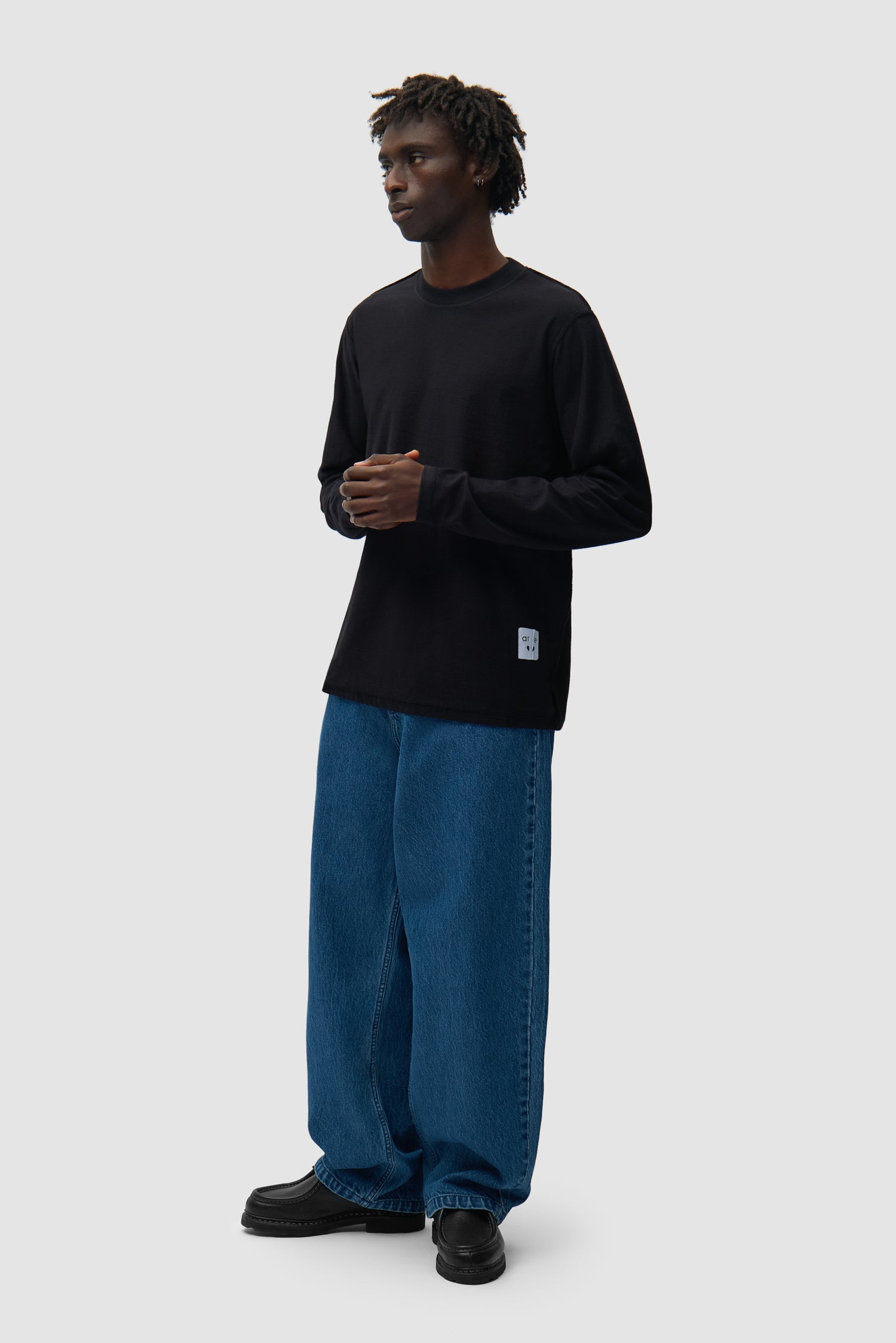 T-shirt à manches longues réversible noir porté par un mannequin, vue de profil en pied