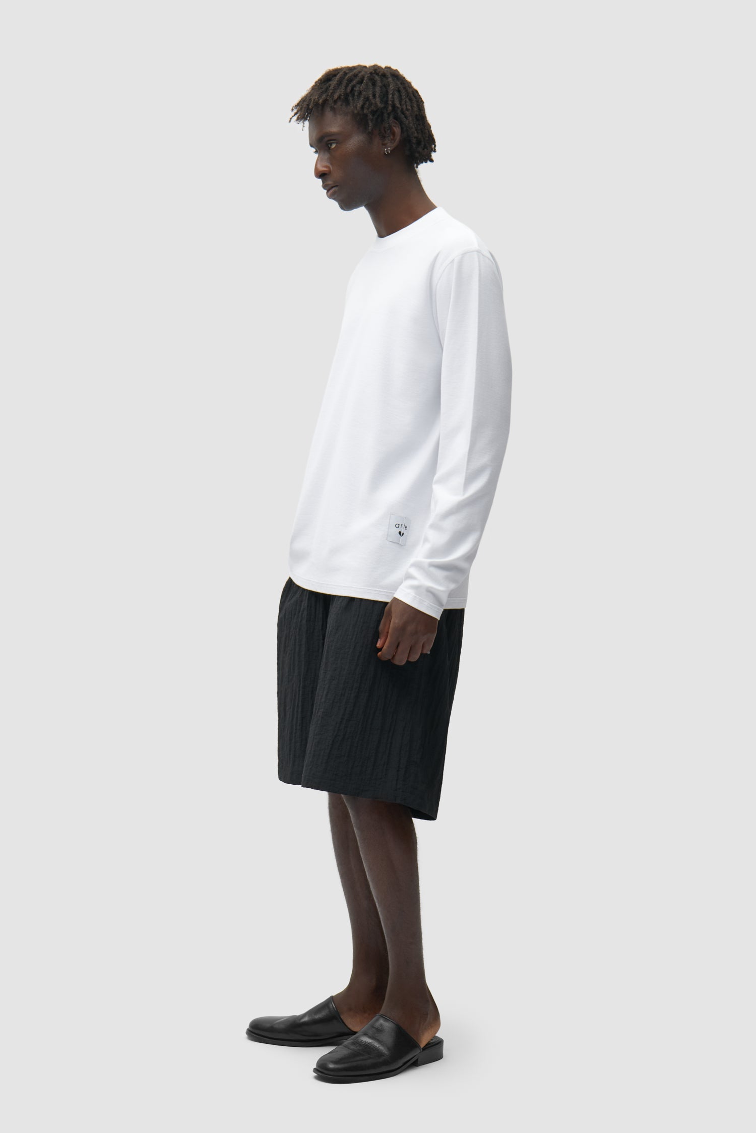 T-shirt à manches longues réversible blanc porté par un mannequin, vue de profil en pied