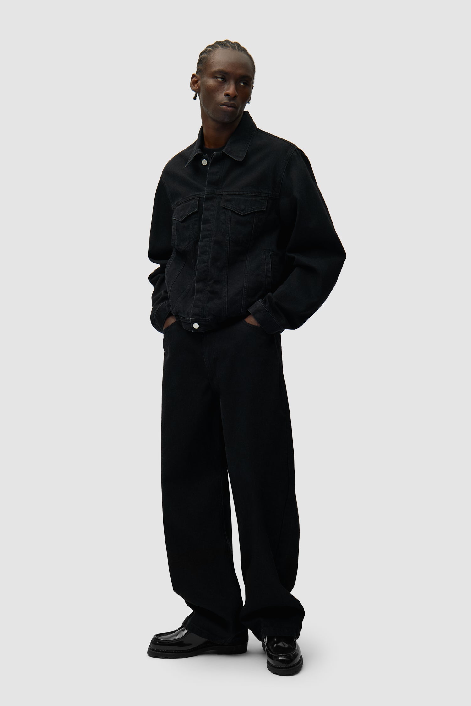 Veste en jean à logo circulaire noire portée par un mannequin, vue de profil en pied