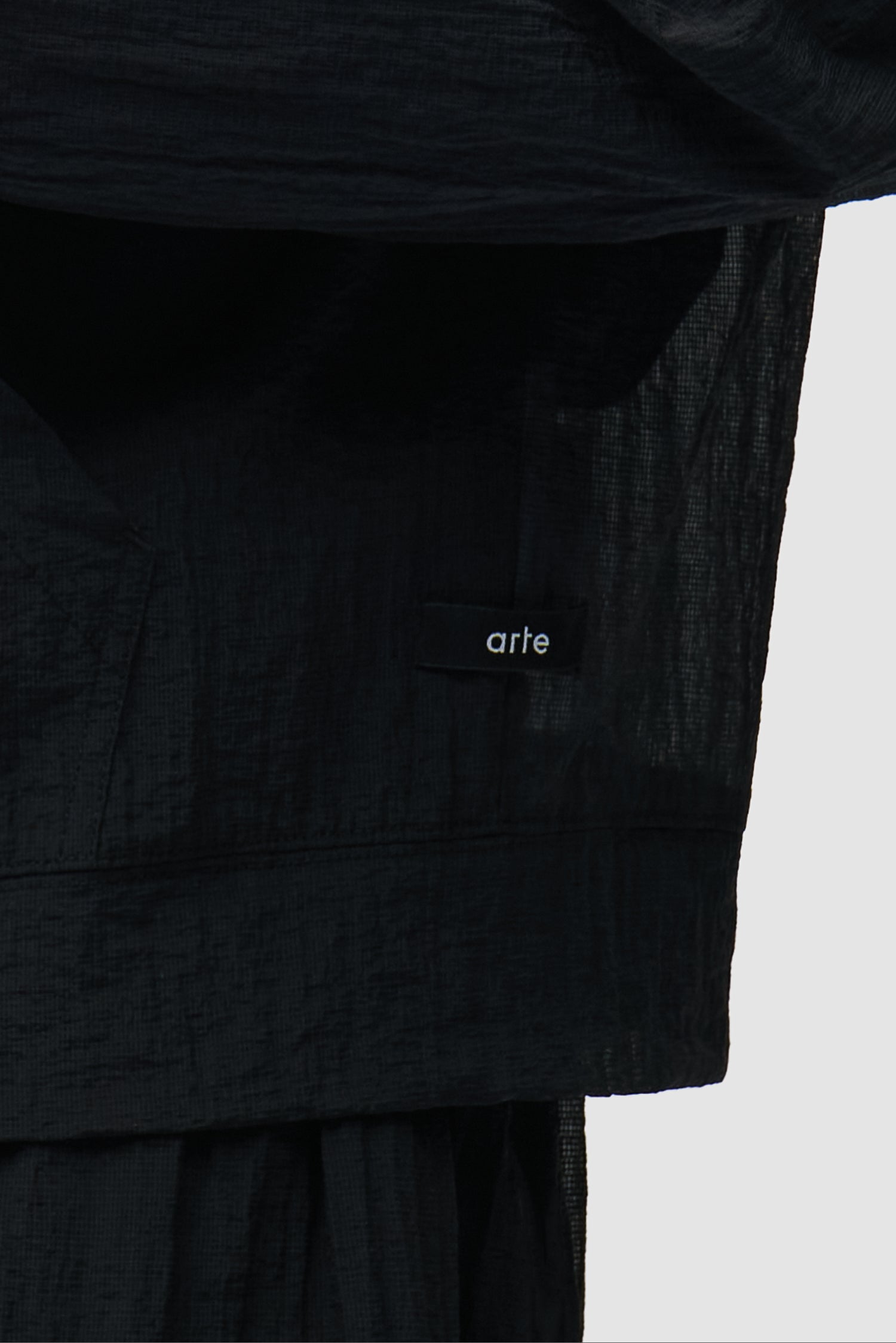 Vue détaillée de la veste en maille noire, avec petit logo