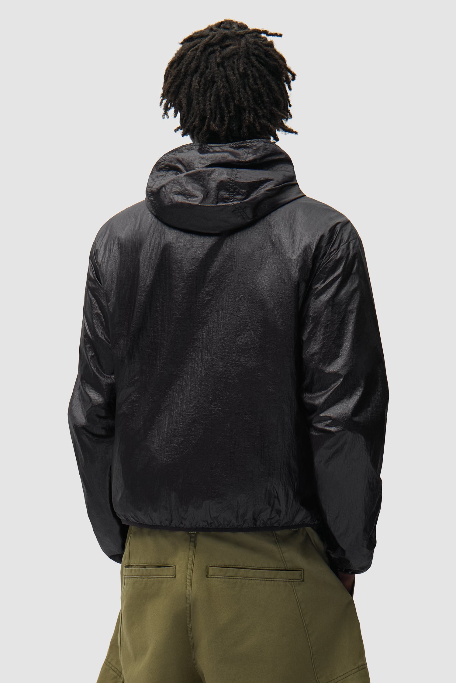 Veste en nylon brillant noire portée par un mannequin, vue de dos à mi-corps