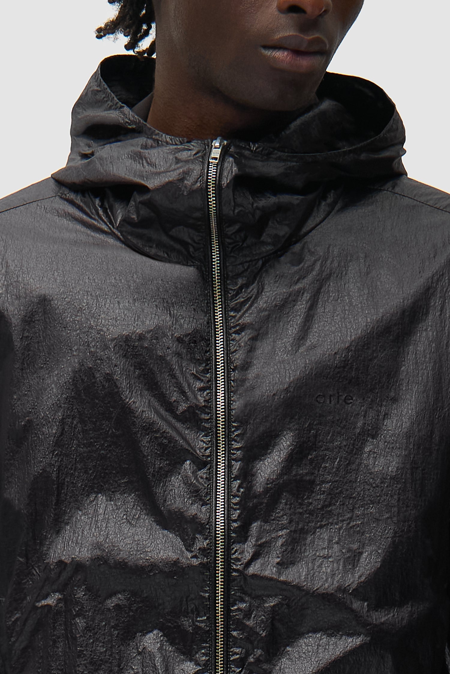 Vue détaillée de la veste en nylon brillant noir, montrant la fermeture éclair à l'avant
