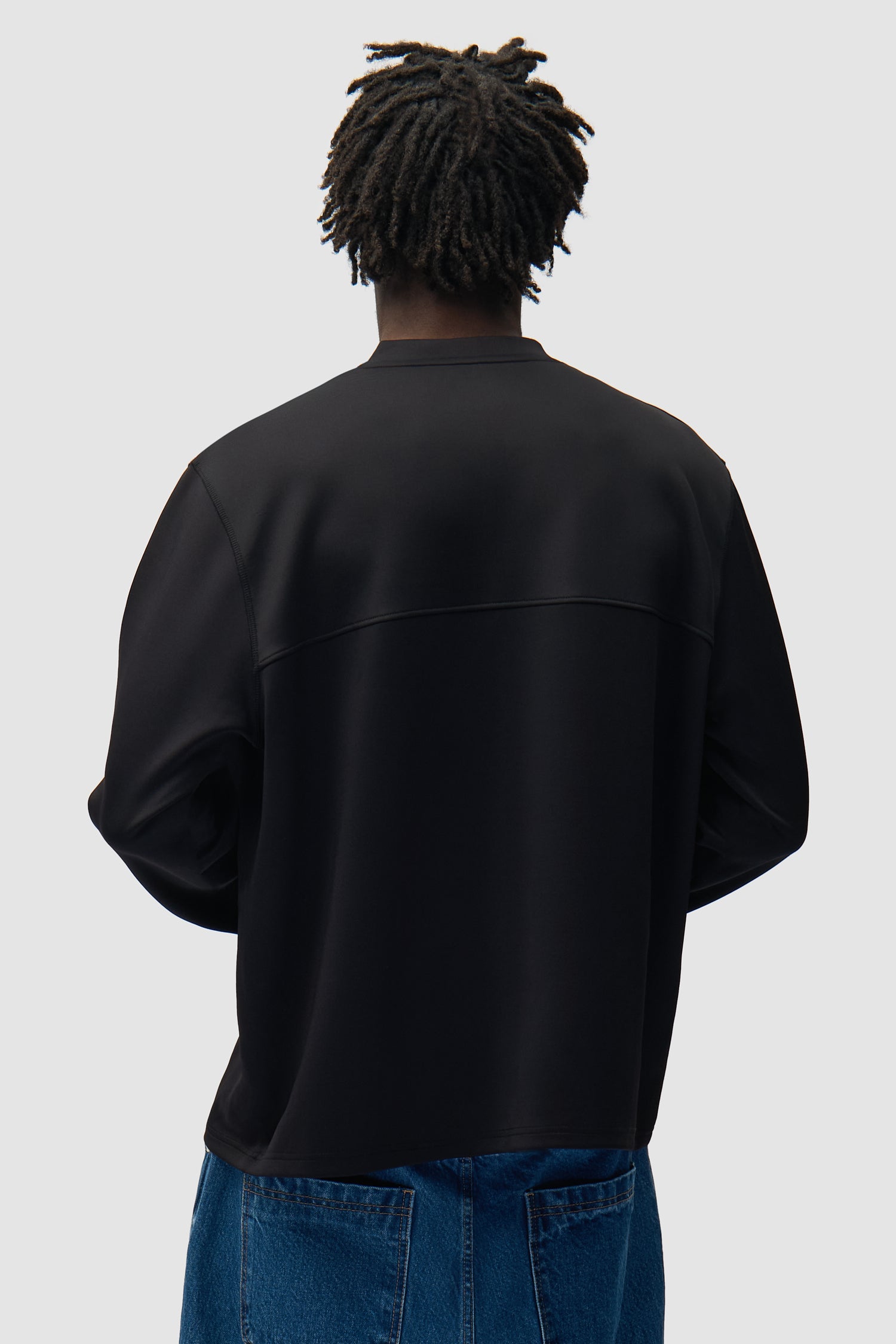 T-shirt à manches longues avec logo circulaire noir porté par un mannequin, vue de dos à mi-corps