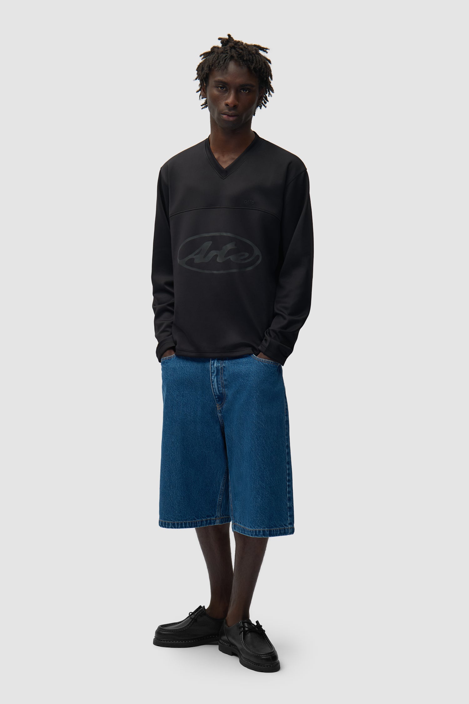 T-shirt à manches longues avec logo circulaire noir porté par un mannequin, vue de profil en pied