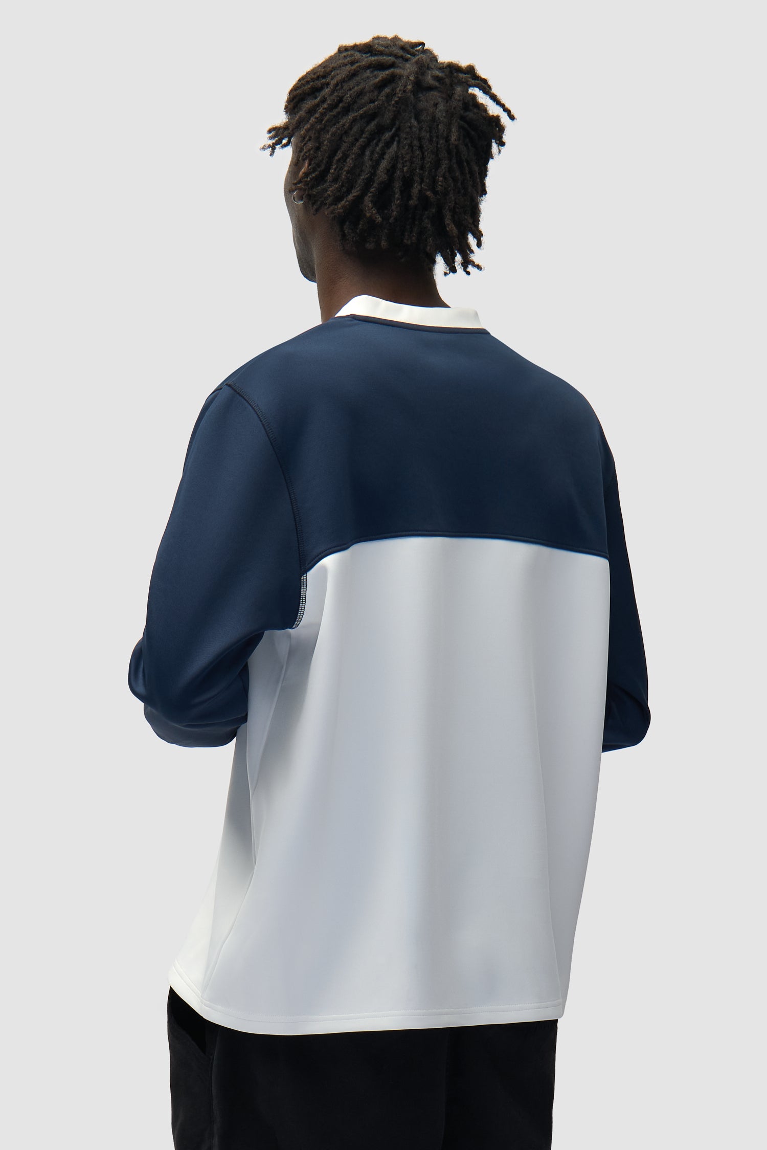 T-shirt à manches longues avec logo circulaire blanc/bleu marine porté par un mannequin, vue de dos à mi-corps