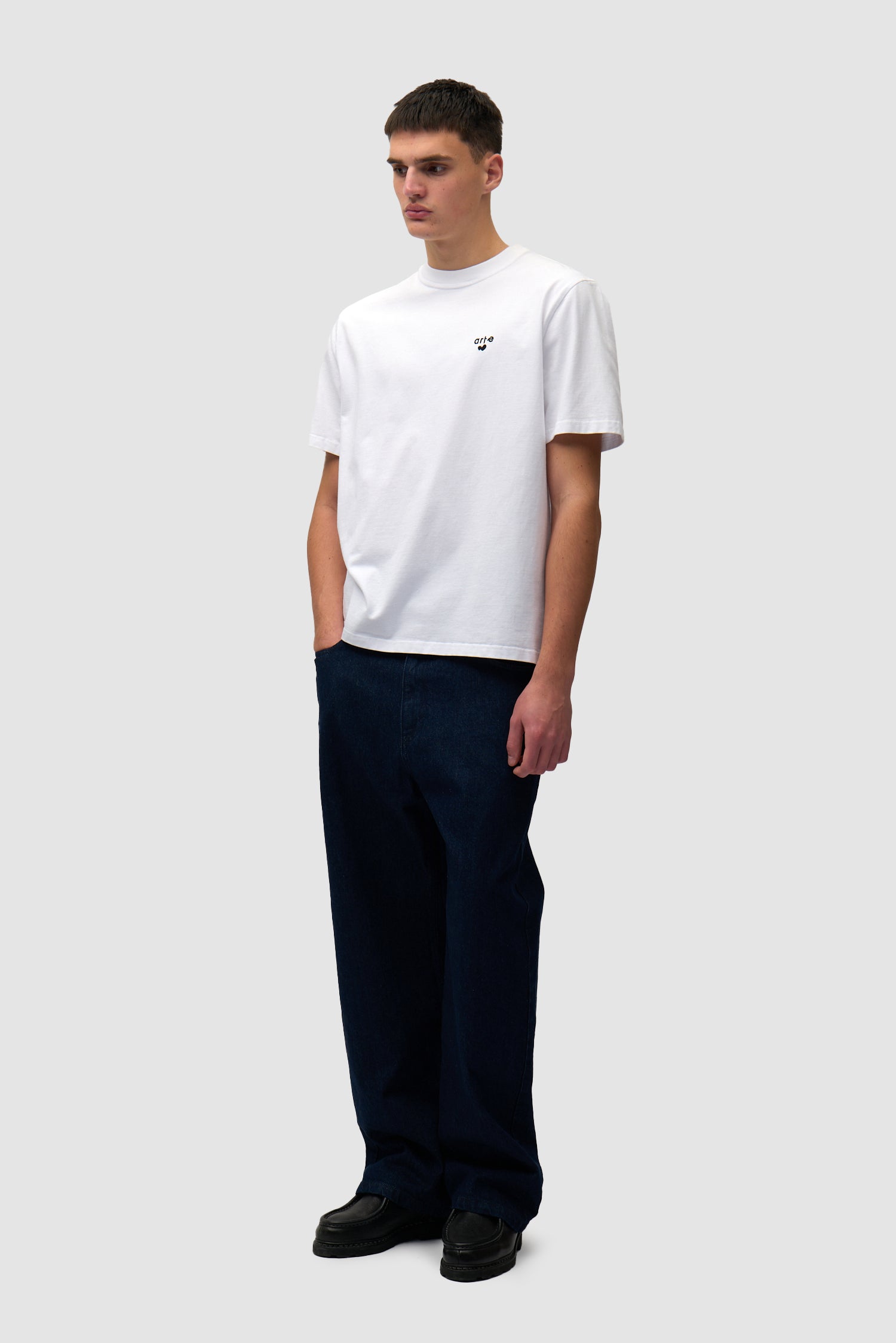 T-shirt blanc avec logo en forme de cœur porté par un mannequin, vue de profil en pied