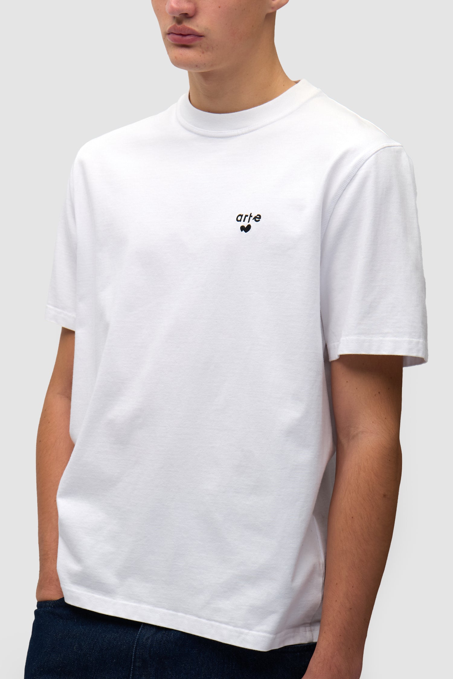 T-shirt blanc avec logo en forme de cœur porté par un mannequin, vue détaillée du haut du corps