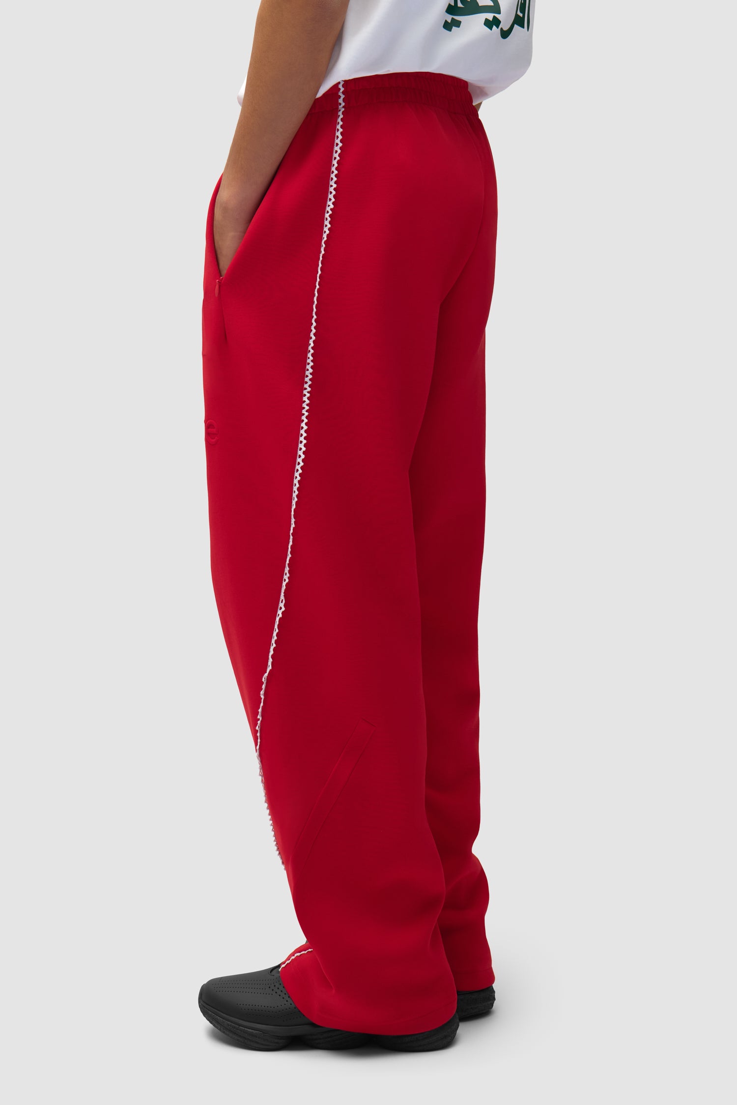 Pantalon Arte pour adidas Z.N.E. en Better Scarlet/White porté par un mannequin, vue de profil à mi-corps