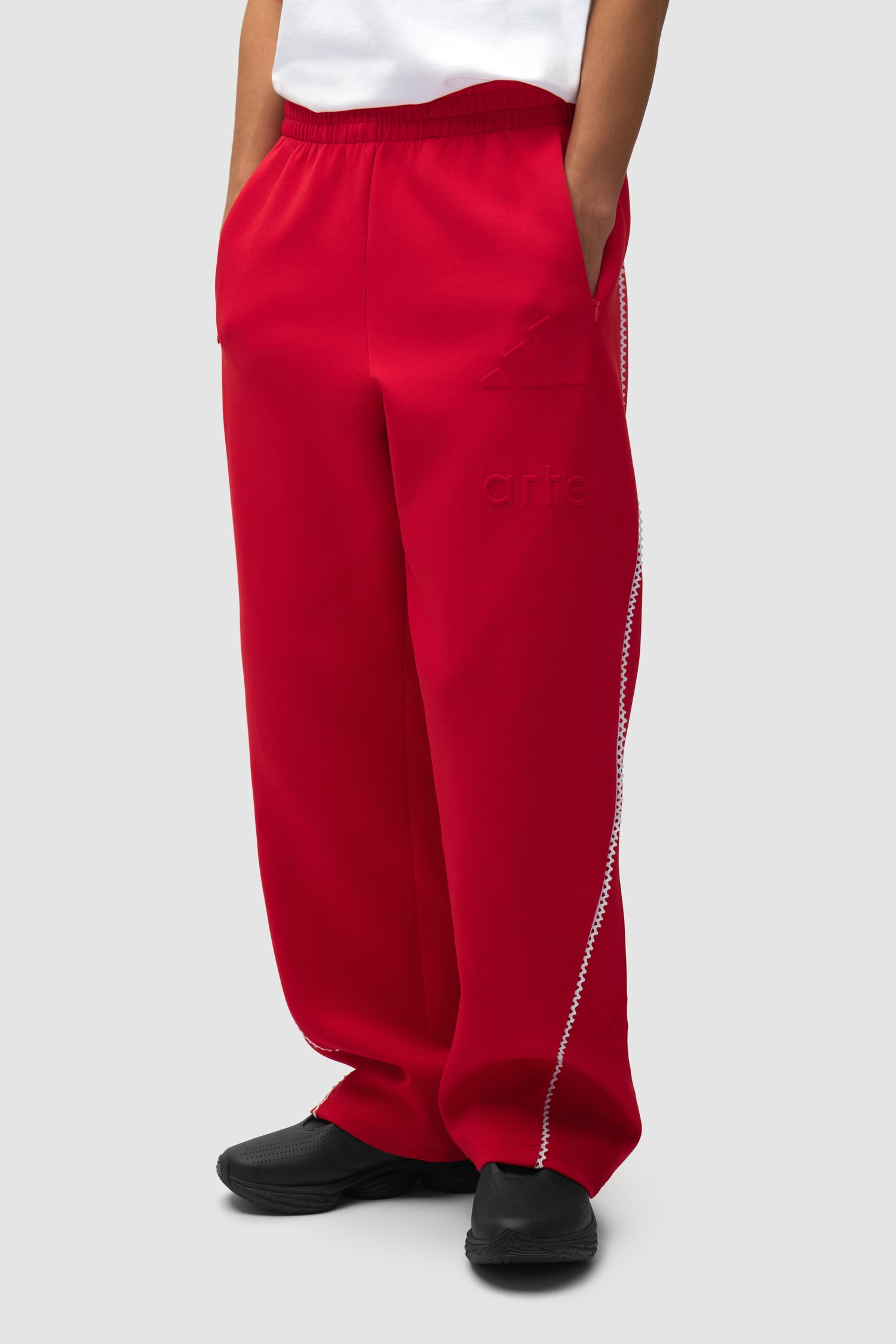 Pantalon Arte pour adidas Z.N.E. en Better Scarlet/White porté par un mannequin, vue de face en demi-corps