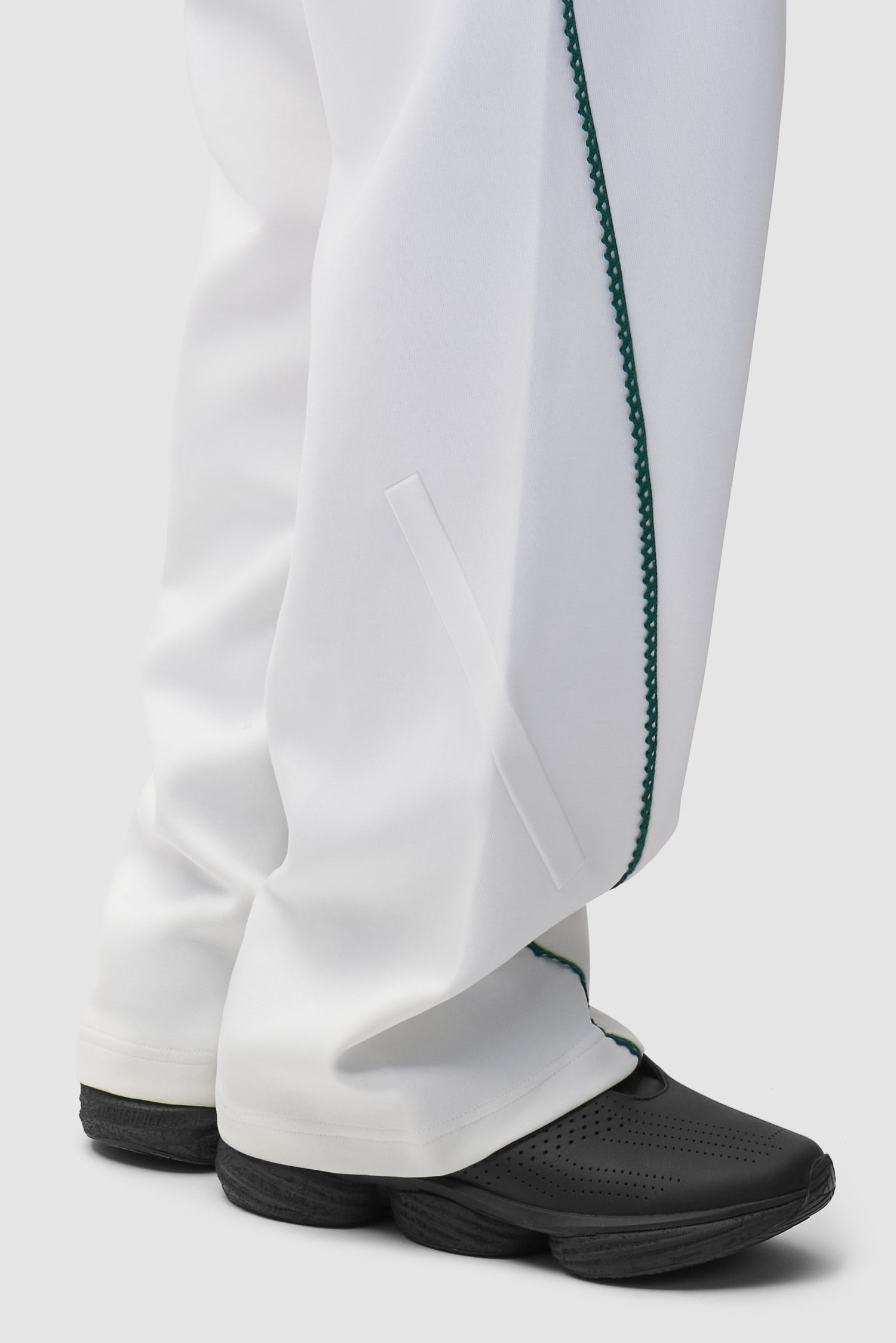 Vue détaillée du pantalon Arte pour adidas Z.N.E. en blanc/Better Scarlet, avec logo en bas.