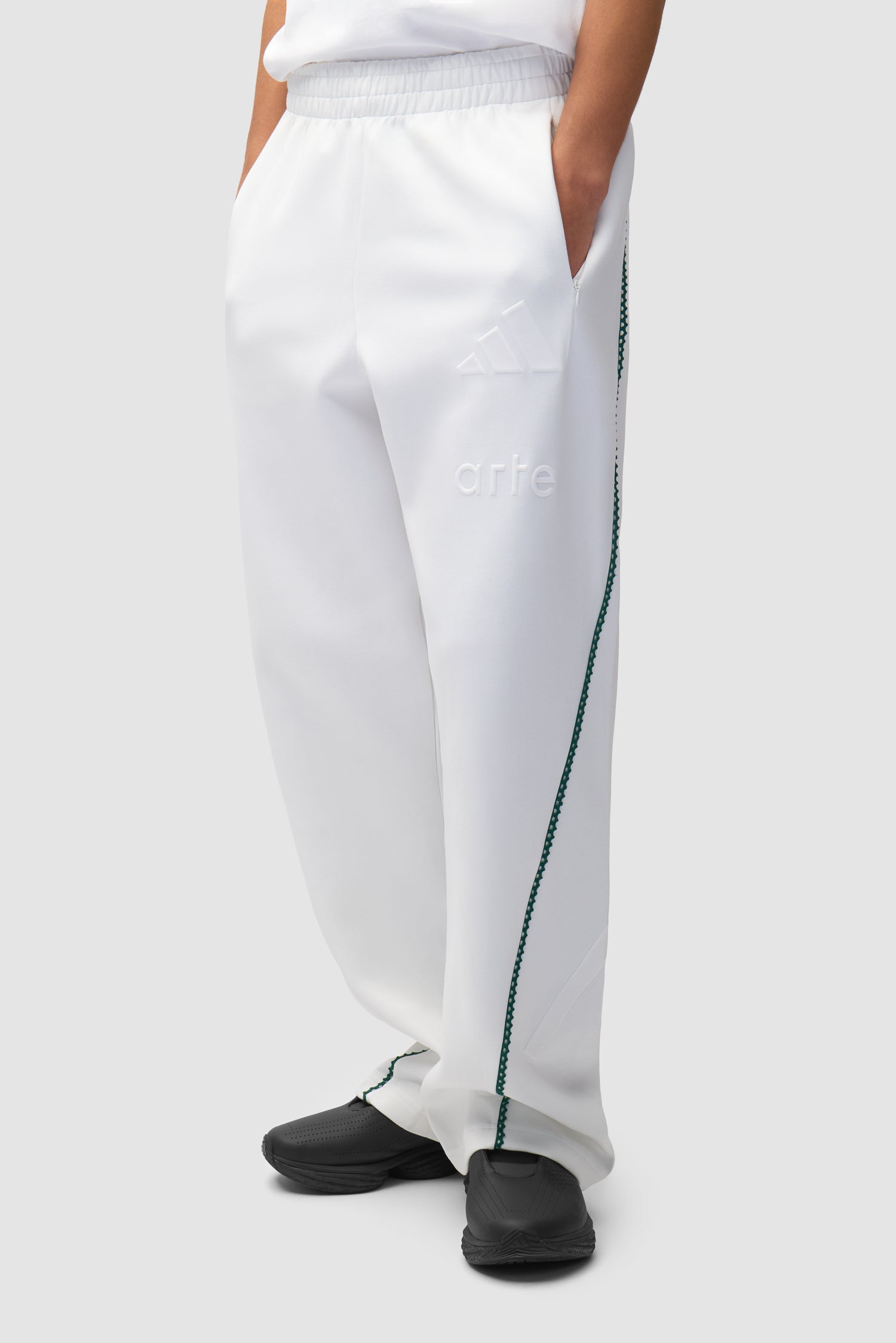 Pantalon Arte pour adidas Z.N.E. en blanc/Better Scarlet porté par un mannequin, vue de face en demi-corps