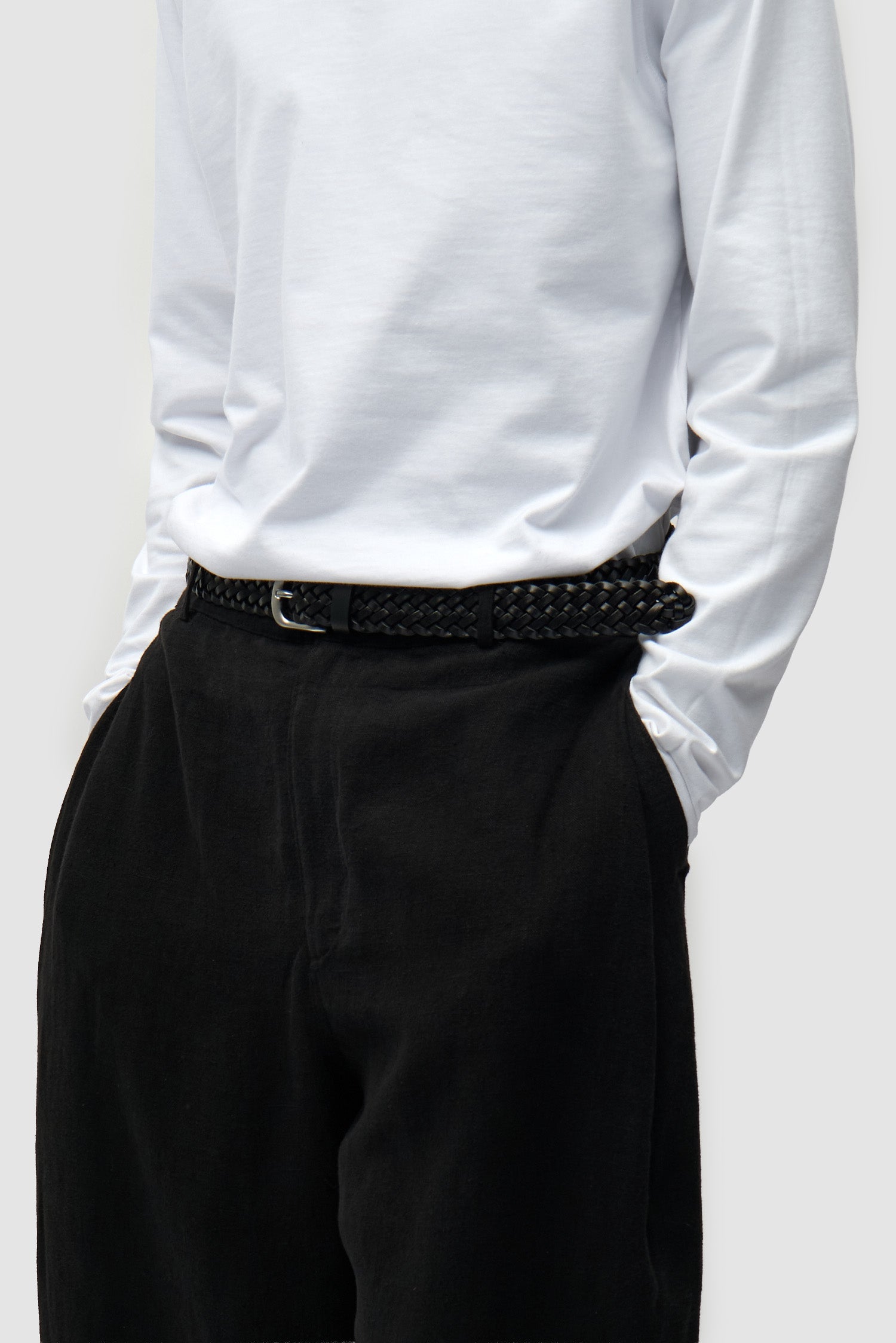 Ceinture en cuir tressé noir portée par un mannequin, vue de demi-corps