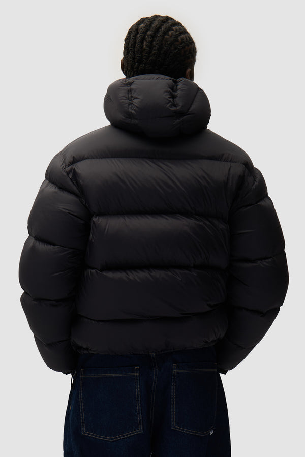 Reversible Puffer Jacket in Black worn by a model, half-body back view
