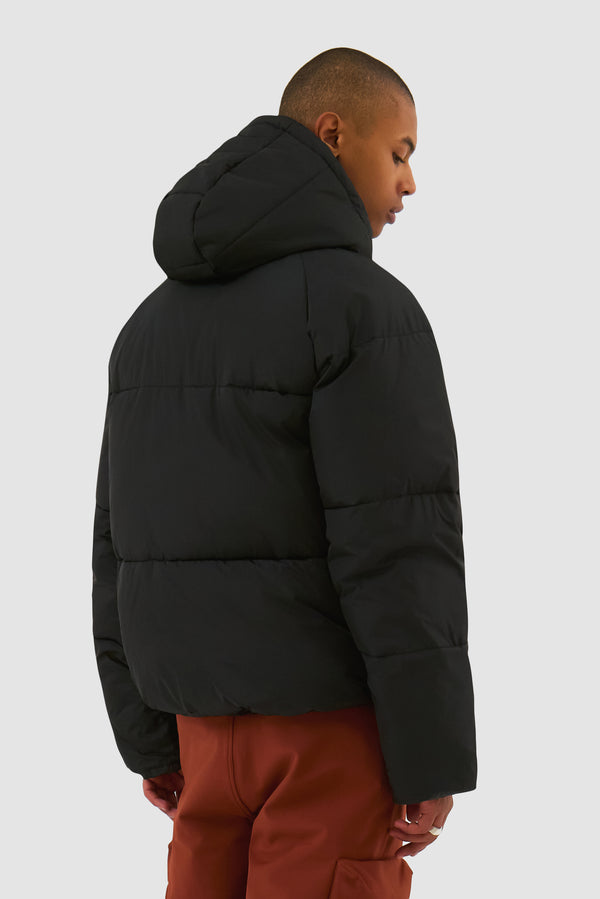 Puffer Jacket in Black worn by a model, half-body back view