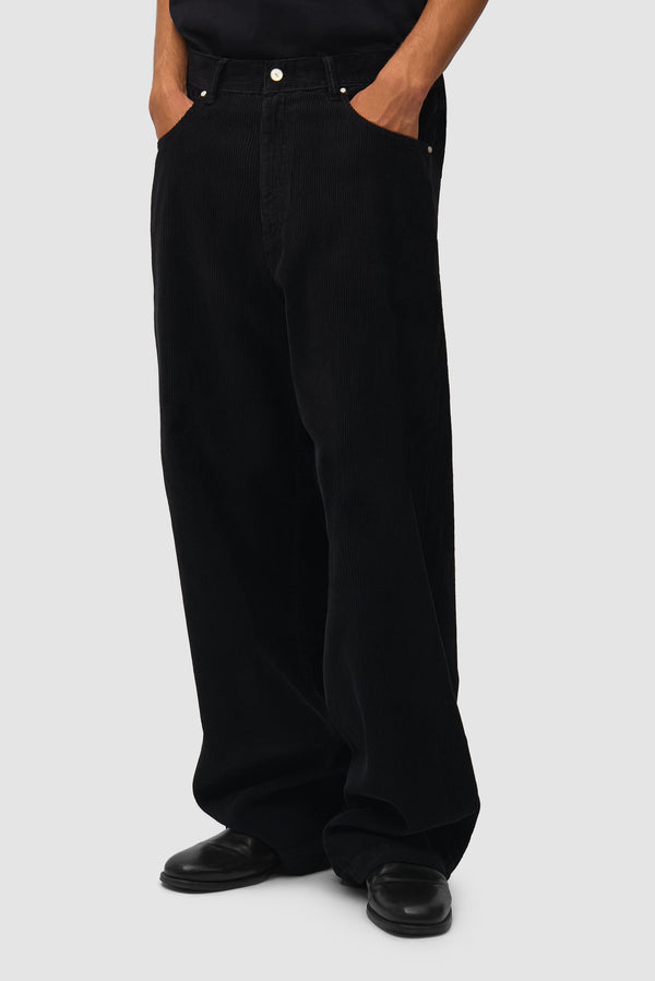 Corduroy Pants in Black worn by a model, half-body back view