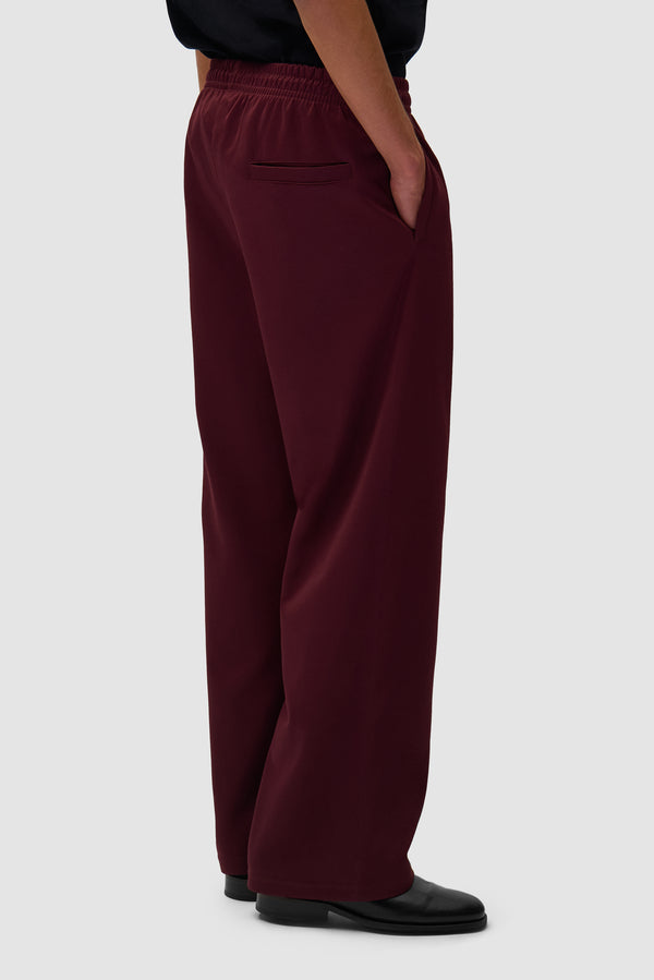 Carded Tracksuit Bottom in Bordeaux worn by a model, half-body back view