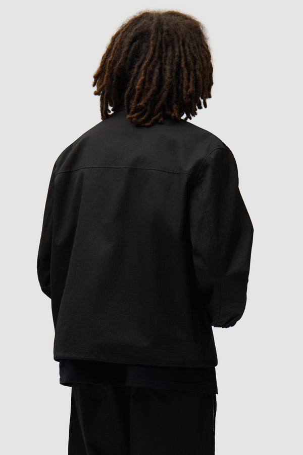 Waxed Ripstop Jacket in Black worn by a model, half-body back view